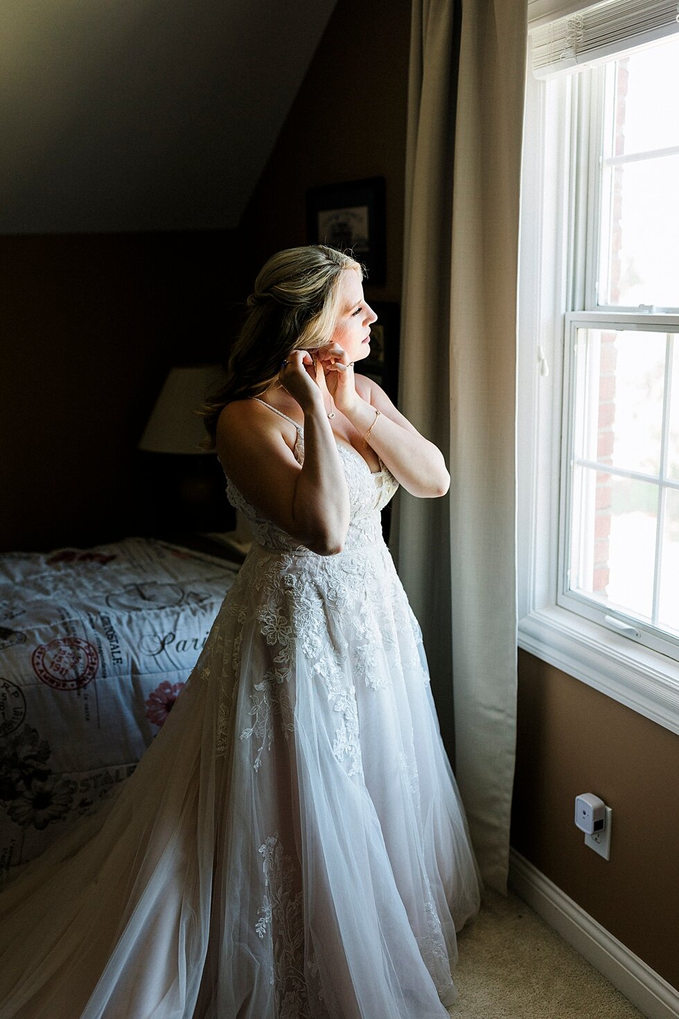  Taking the final moments as she prepares to walk down the aisle to apply the last minute accessories to her ensemble. Romantic casual lace wedding gown close friends neutral colors background wedding natural greenery crisp white #midwestphotographer