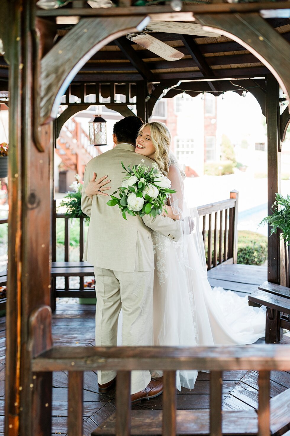  Hugging under the gazebo as this couple ties the knot. Romantic casual lace wedding gown close friends neutral colors background wedding natural greenery crisp white #midwestphotographer #kywedding #louisville #kentuckywedding #louisvillekyweddingph