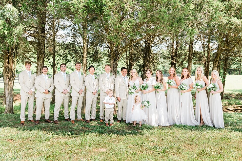  From the brides side to the grooms, this couple had so many wonderful people to support them on their big day including the entire wedding party! Romantic casual lace wedding gown close friends neutral colors background wedding natural greenery cris
