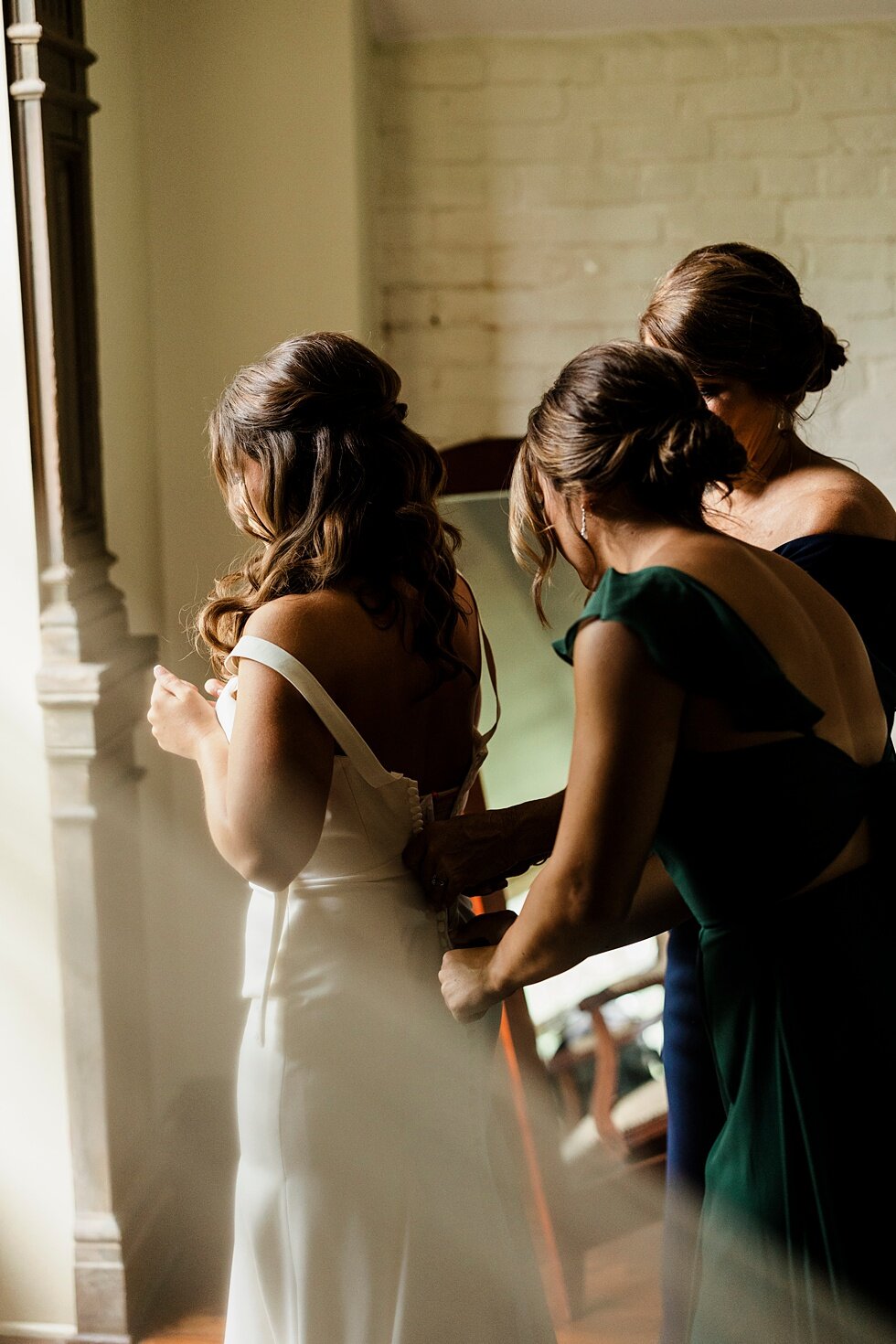  Bridesmaids helping the bride zip up her stunning white wedding gown on her wedding day as they get ready for her to get married. Kentucky wedding photographer wedding bliss just married love ceremony inspiration garden wedding intimate #farmingtonh