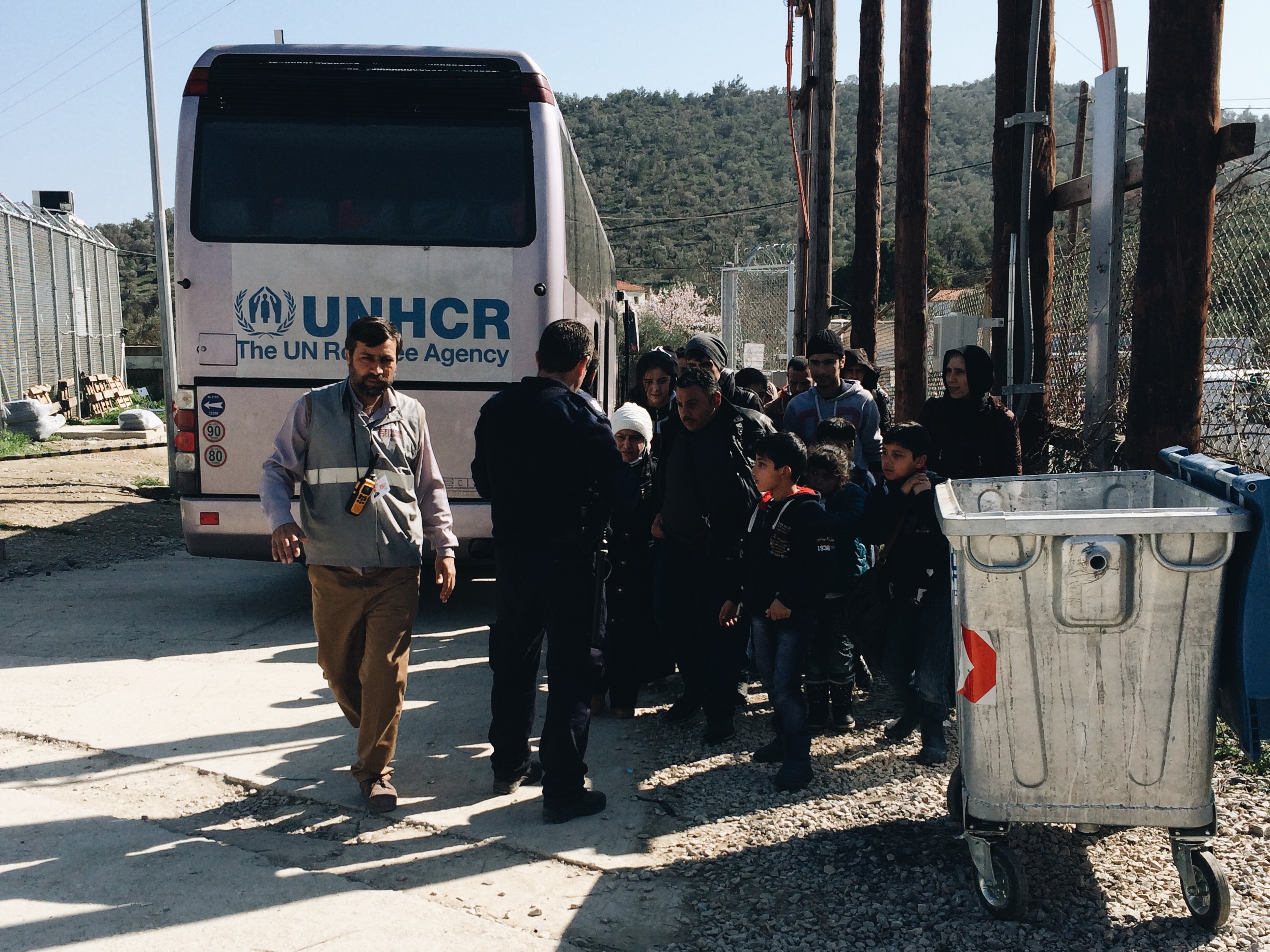 Refugees being received from UNHCR buses and given tickets with their registration numbers on them.