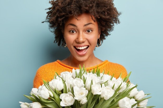 headshot-curly-joyous-ethnic-girl-smiles-happily-shows-white-perfect-teeth-holds-big-bunch-tulips-glad-receieve-flowers-from-husband-dressed-casual.jpg