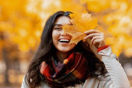 lovely-millennial-woman-smiling-and-closing-her-eye-with-yellow-autumn-leaf-during-her-walk-at-park-in-fall-portrait-of-happy-young-lady-spending-time-outdoors-.jpg