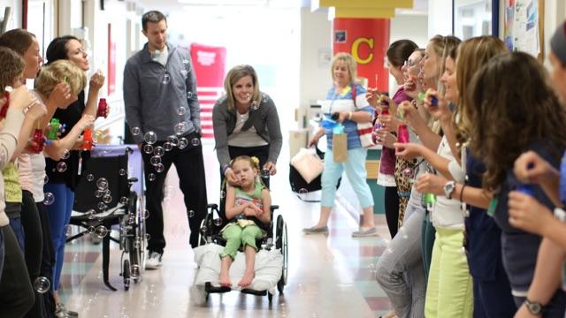 Nurses and therapists gather to blow bubbles for Kycie as she leaves her pod and goes back home.