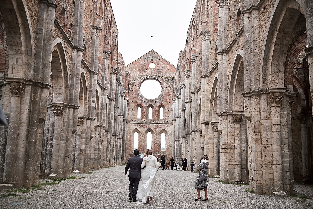  Intimo matrimonio invernale nella splendida cornice della basilica di San Galgano, a Chiusdino in provincia di Siena. Un rito civile sancito dal sindaco sotto il cielo, in quanto la struttura è priva di tetto. Un luogo magico, un allestimento florea