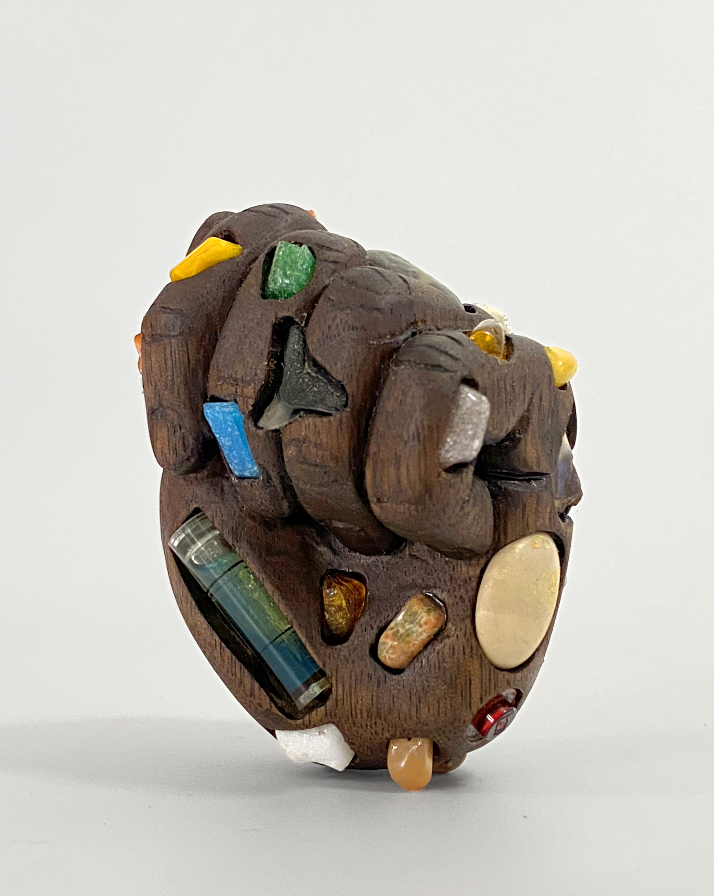   Gift Hand , 2023, fossils, amber, glass, rocks, plastic level, and Legos on carved walnut, 3” x 2.5” x 2” 