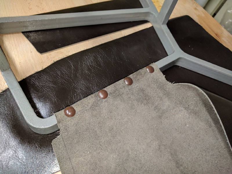  I attached the leather with furniture tacks I had on hand and rubber cement. &nbsp;If I make a similar project in the future I'll look for smaller tacks that don't stick out past the width of the rail. 