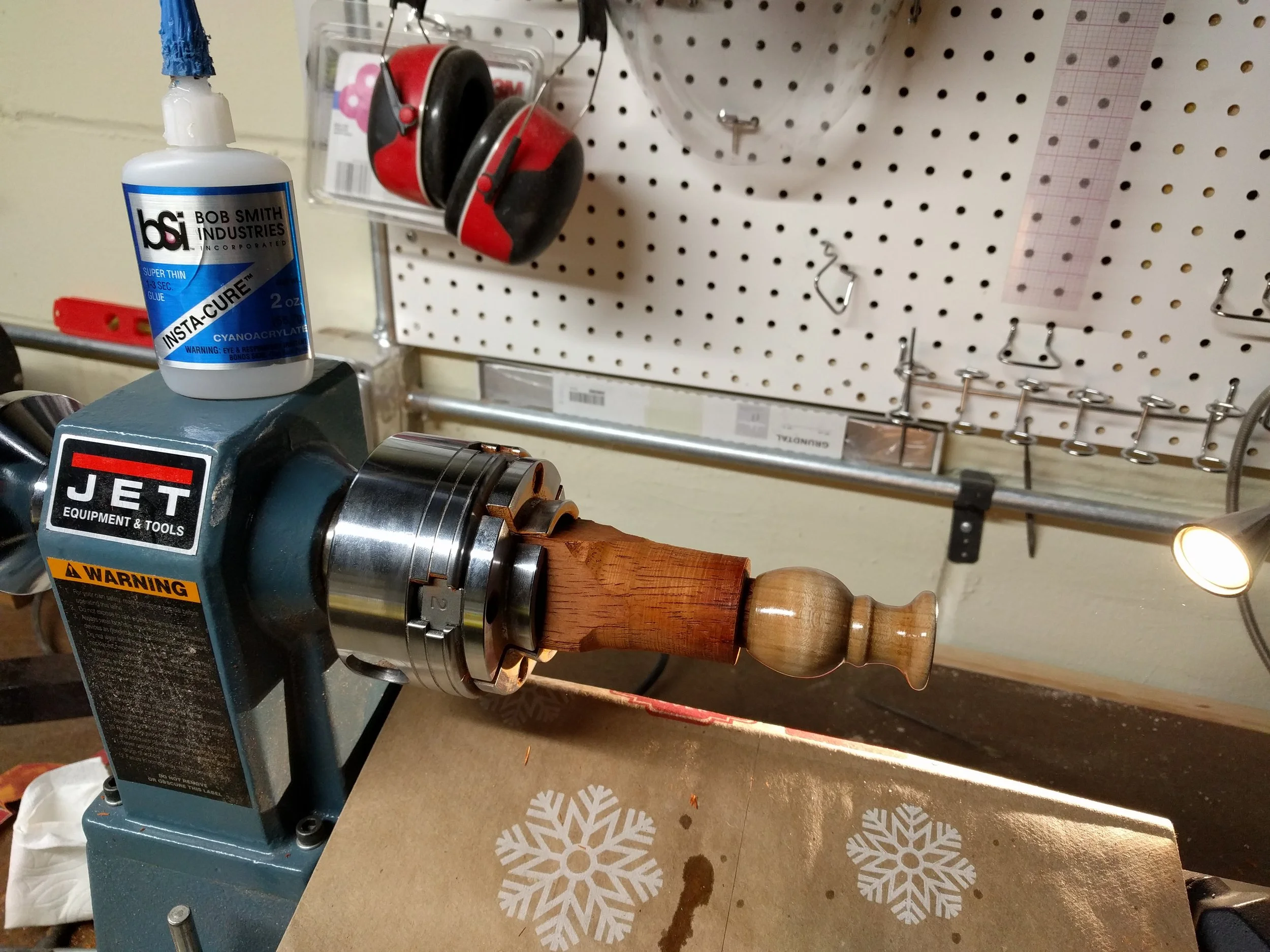 Parted off the stock and mounted on a jam chuck. This allows you to sand the bottom and apply the final finish. I chose CA glue applied in about a dozen thin coats for durability.