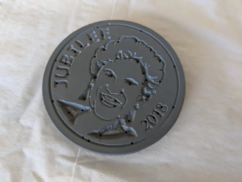  I cut the coin out with a band saw and cleaned up the edges on a belt sander.  Next time I will adjust the angle of the sanding table a couple of degrees to add a slight draft.  The last step was drilling lots of tiny holes for the air to escape fro