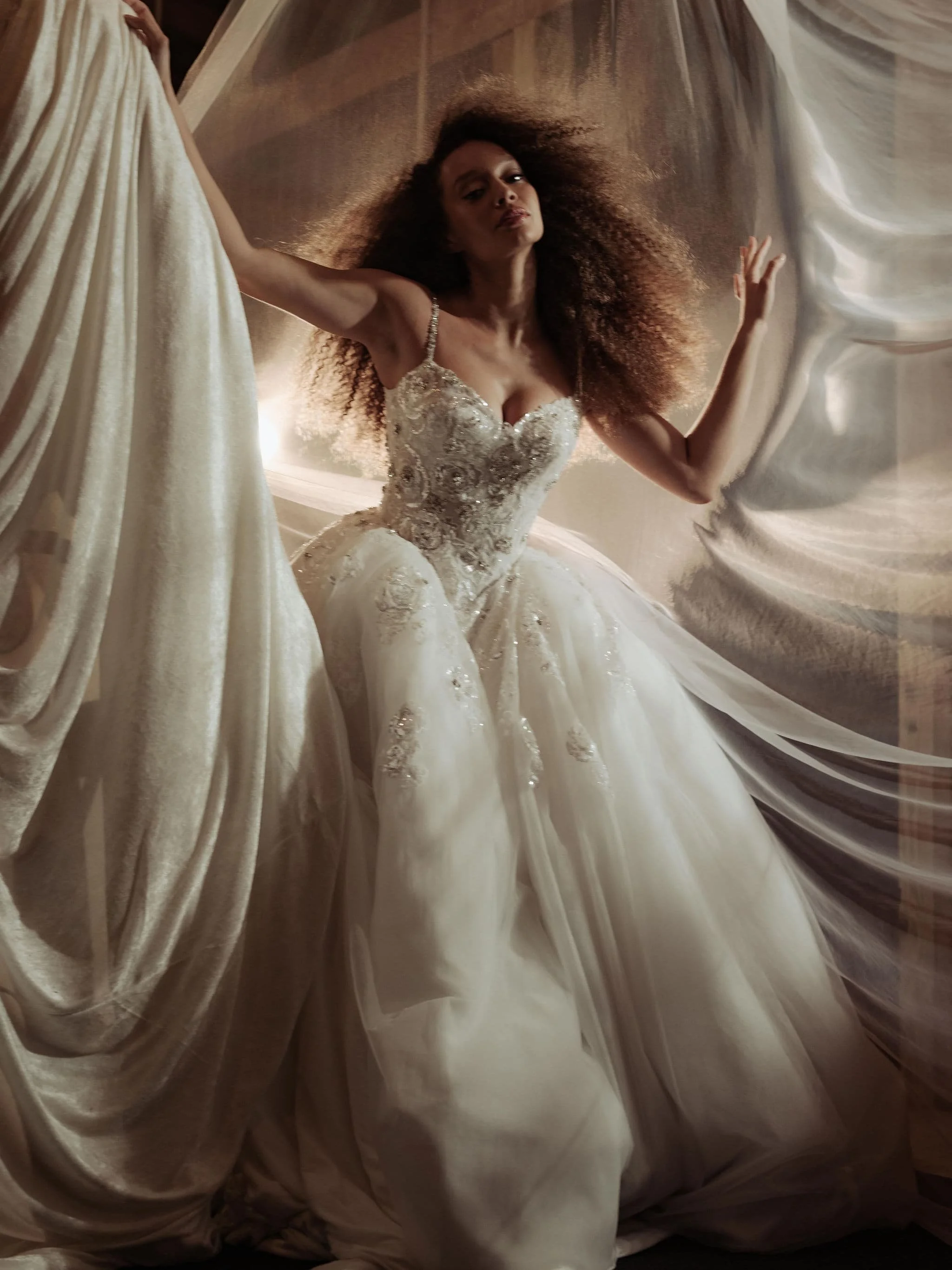 curly hair model in wedding gown on gorgeous  set made from veils and drapery