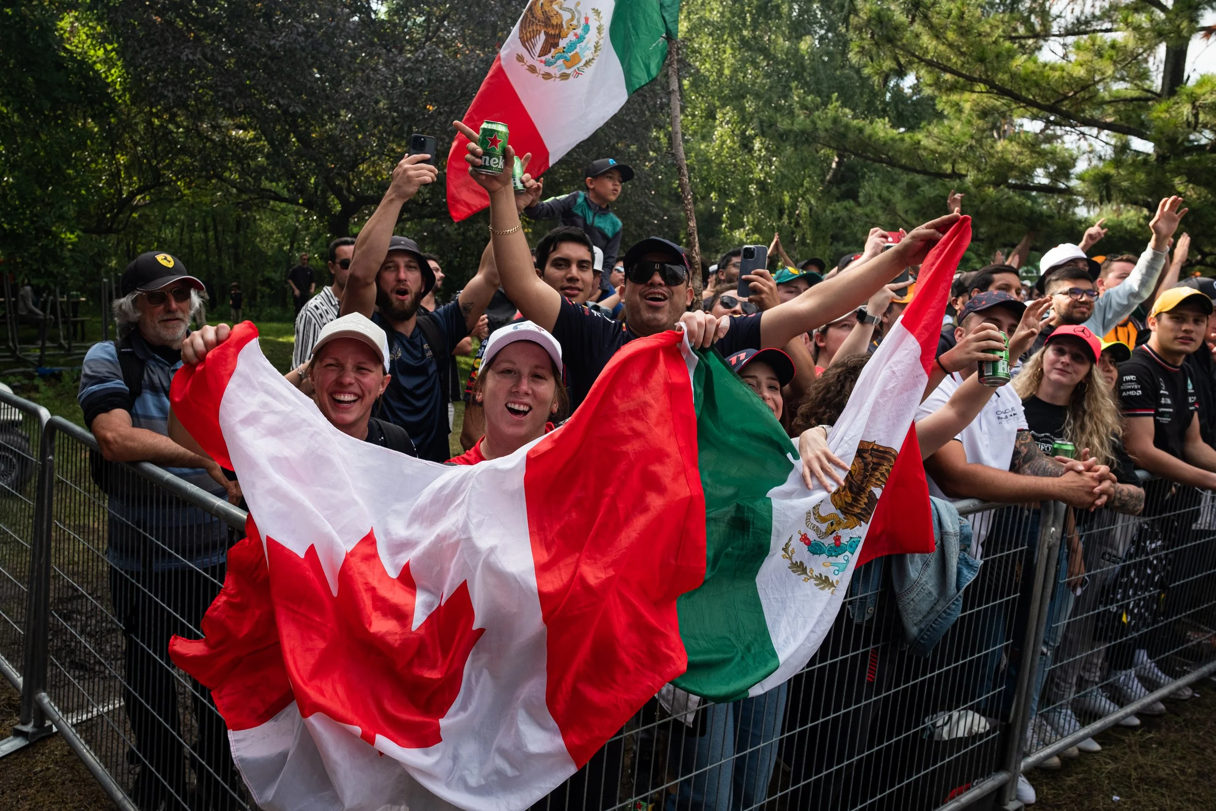 Crowd of people cheering and celebrating, waving Mexican flags at an outdoor event.