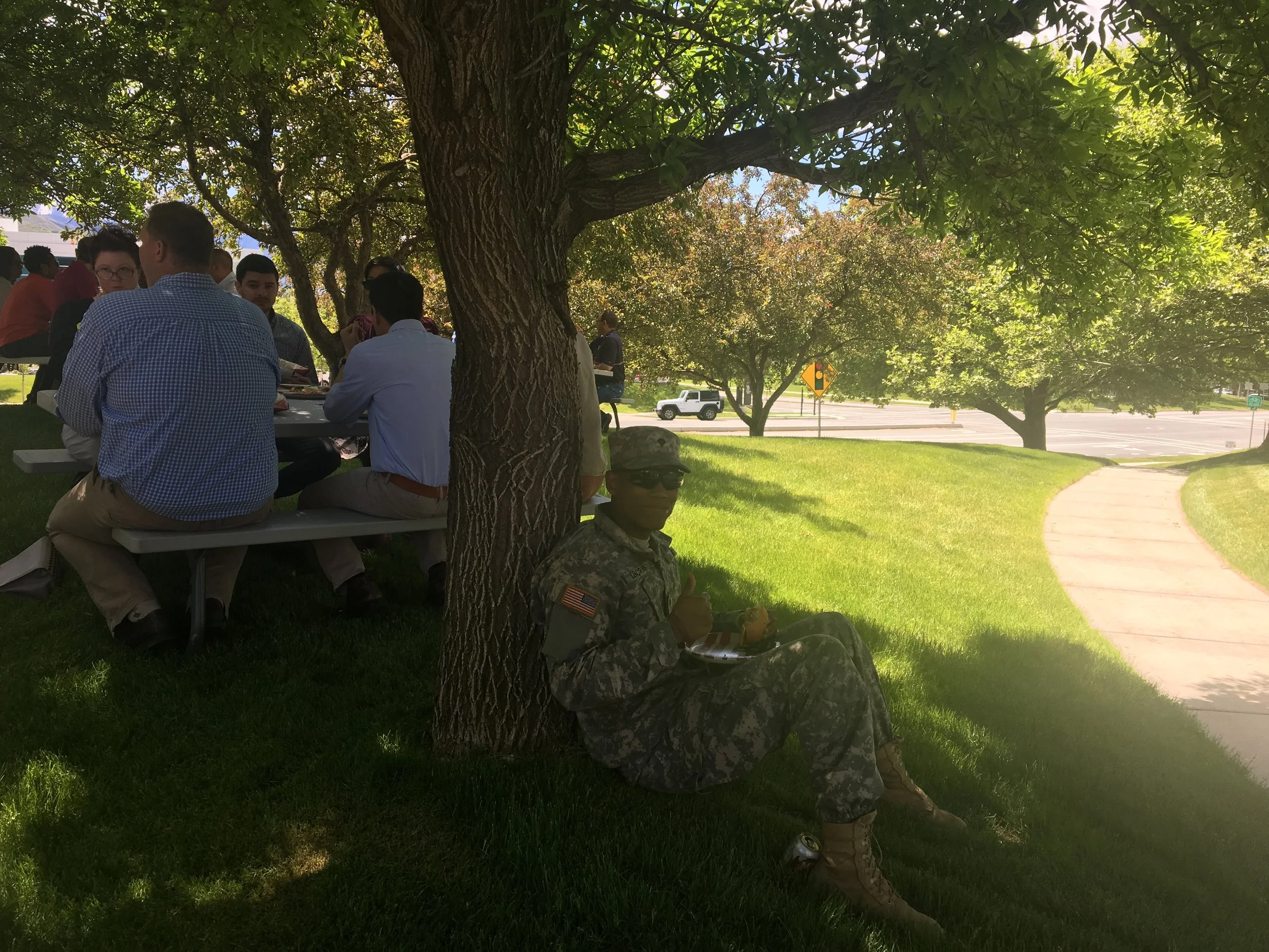 Soldier sitting in the shade enjoying his burger. 