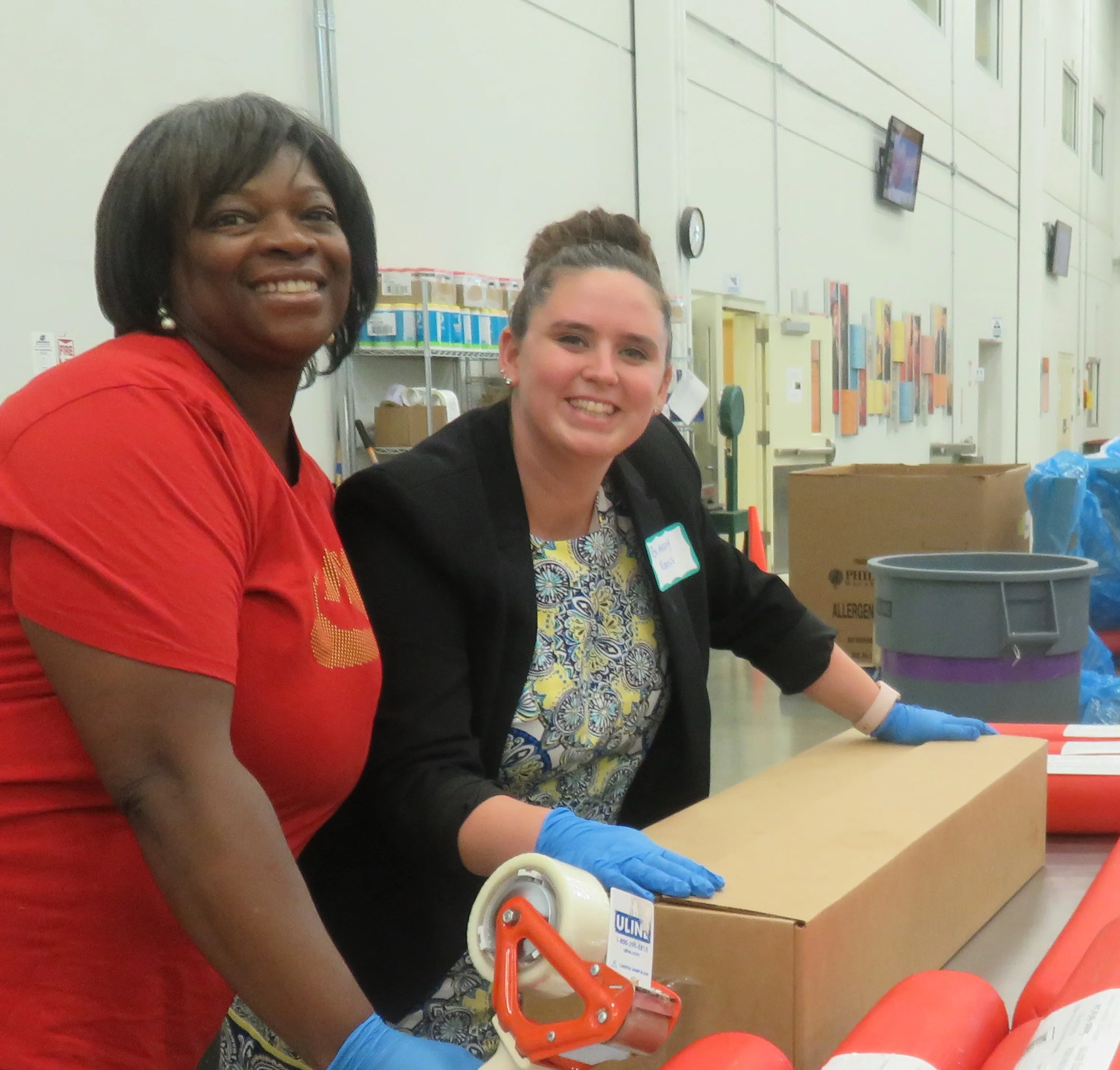 Patricia Quinn (Director of HR) & Brittany Norris (Catering Sales Manager) help box up 36 pounds of bologna! Photo courtesy of the Northern IL Food Bank.