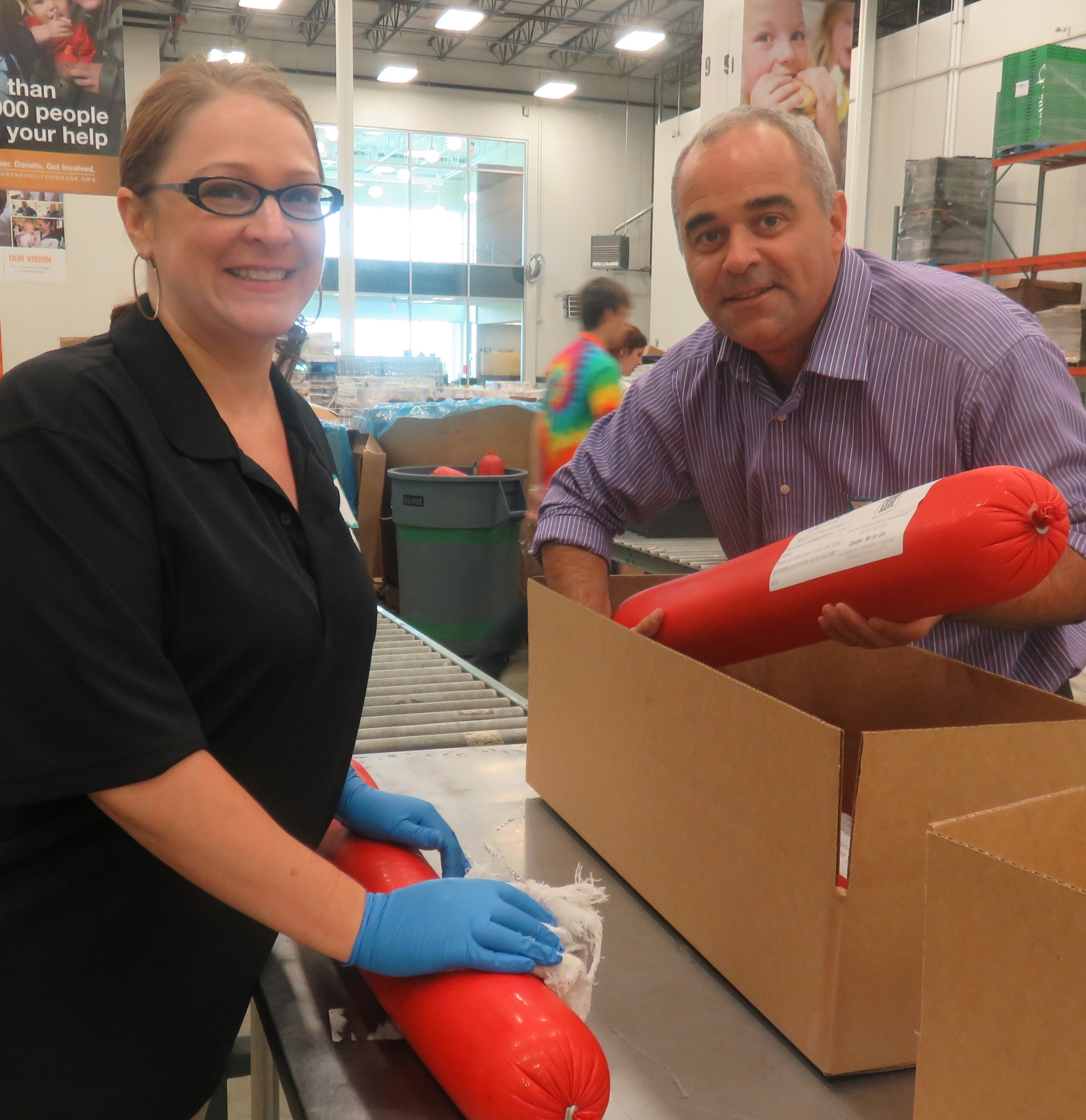 Lisa K. Adams (Marketing Manager) & Mathias Dalbera (Director of Revenue) place labels on bologna before boxing it up. Photo courtesy of the Northern IL Food Bank.