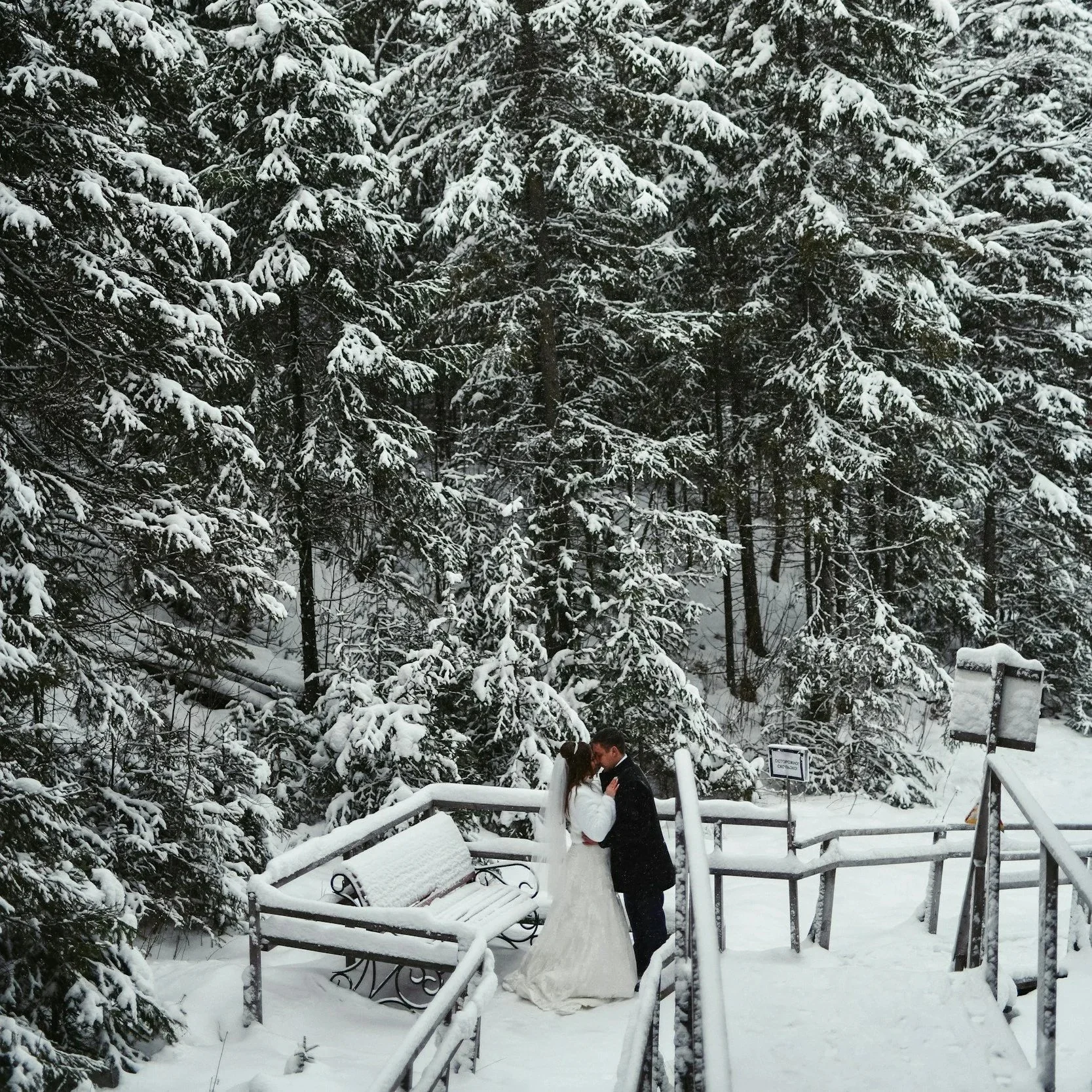Bride and groom sharing a romantic moment during a snowy winter wedding in a forest setting