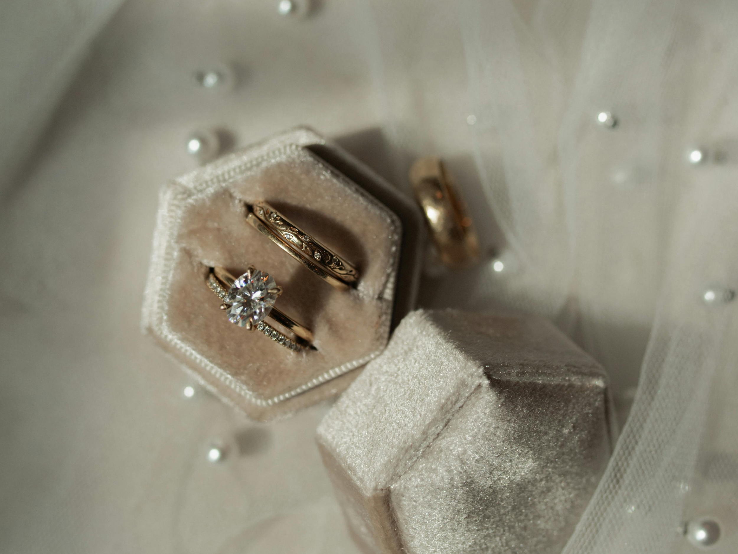 Engagement and wedding rings displayed in a velvet ring box on soft fabric
