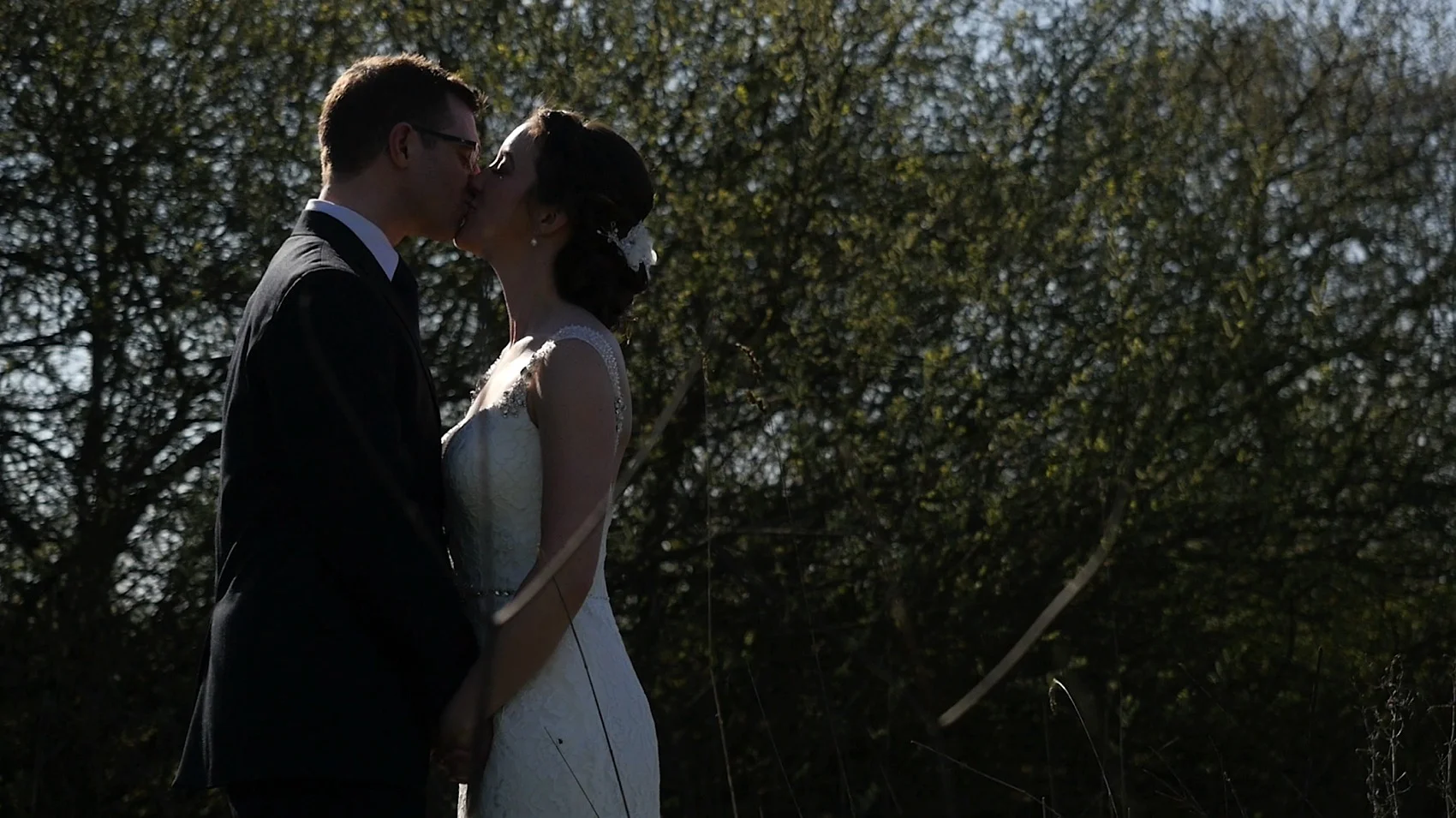 Tom and Laura share a kiss beside the lake at Styal Lodge during their Wedding Video.