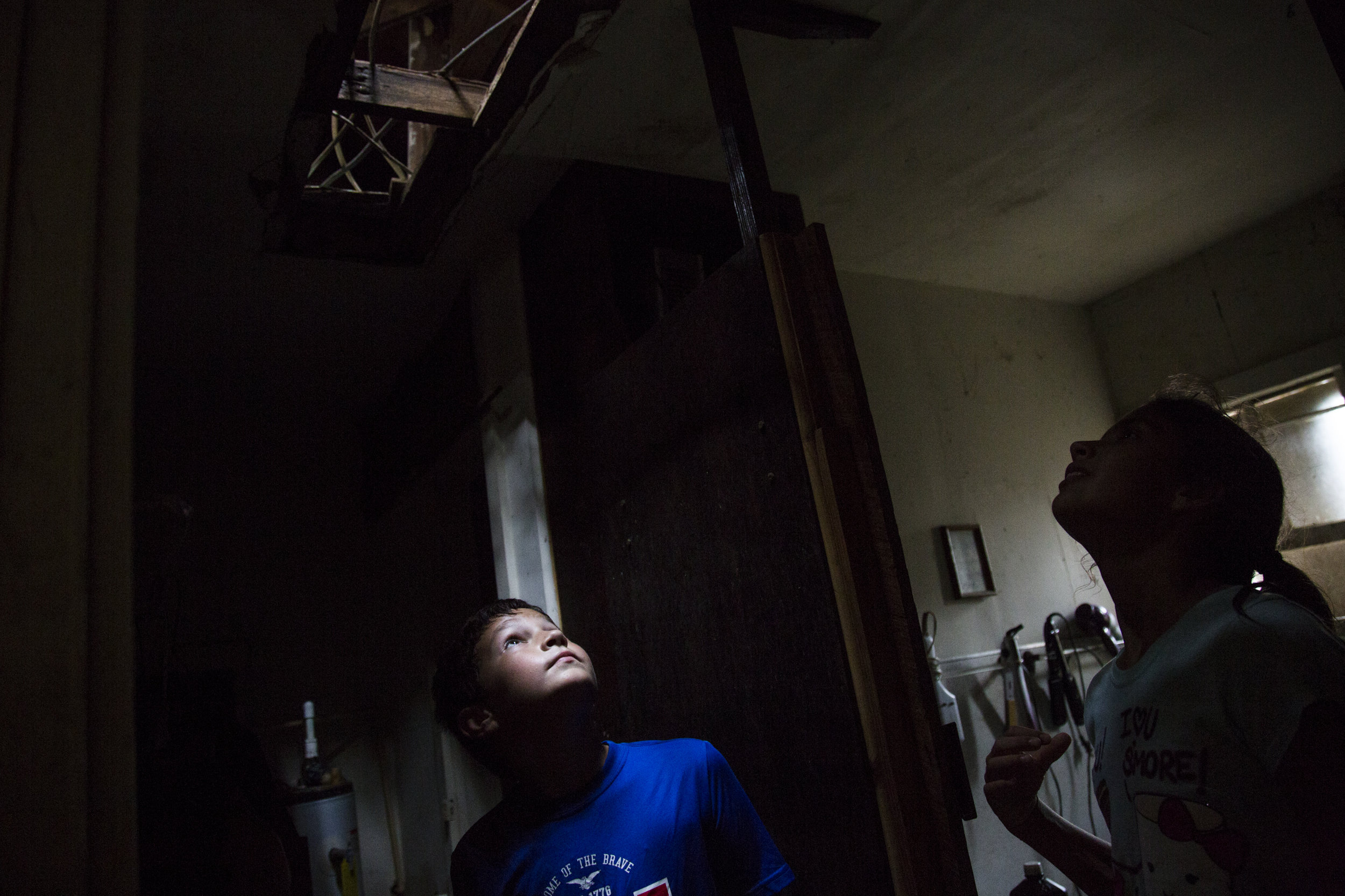 Kyler Carpenter, 10, left, and Laela Carpenter, 11, look up through a hole that was torn in their roof by Hurricane Harvey. The cousins surveyed the damage on Aug. 27, 2017 to Laela’s family home in Bayside, Texas.