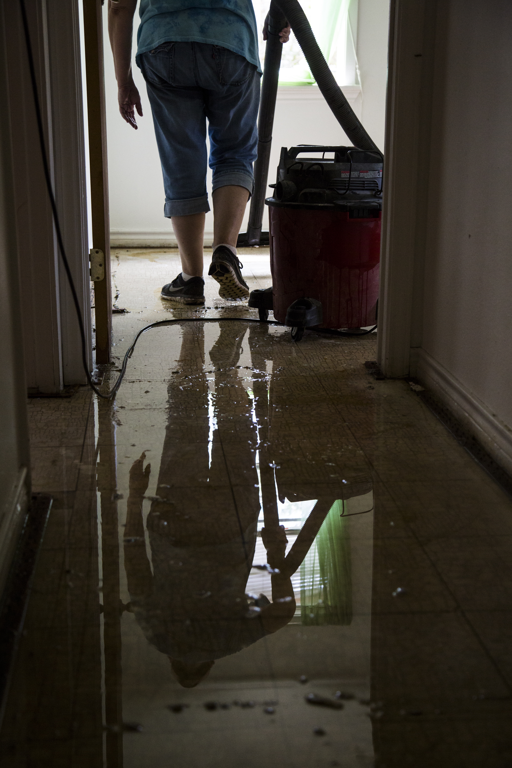 Susie Starkey helps vacuum up leftover floodwater from the Hamilton's home in Greens Addition.