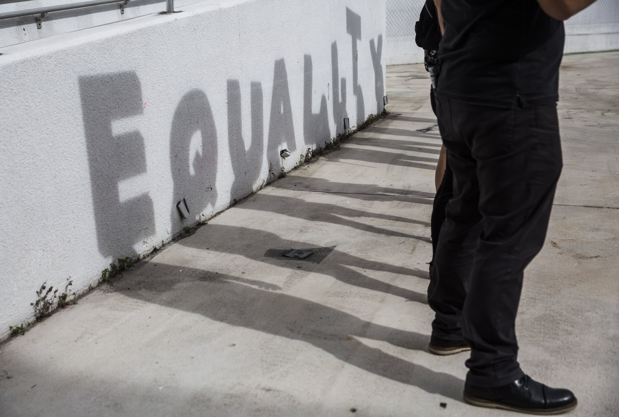 A shadow spelling out "equality" is cast against a wall as a part of an art piece set up at the Women's March Florida at Mana Wynwood in Miami on Jan. 21, 2018.