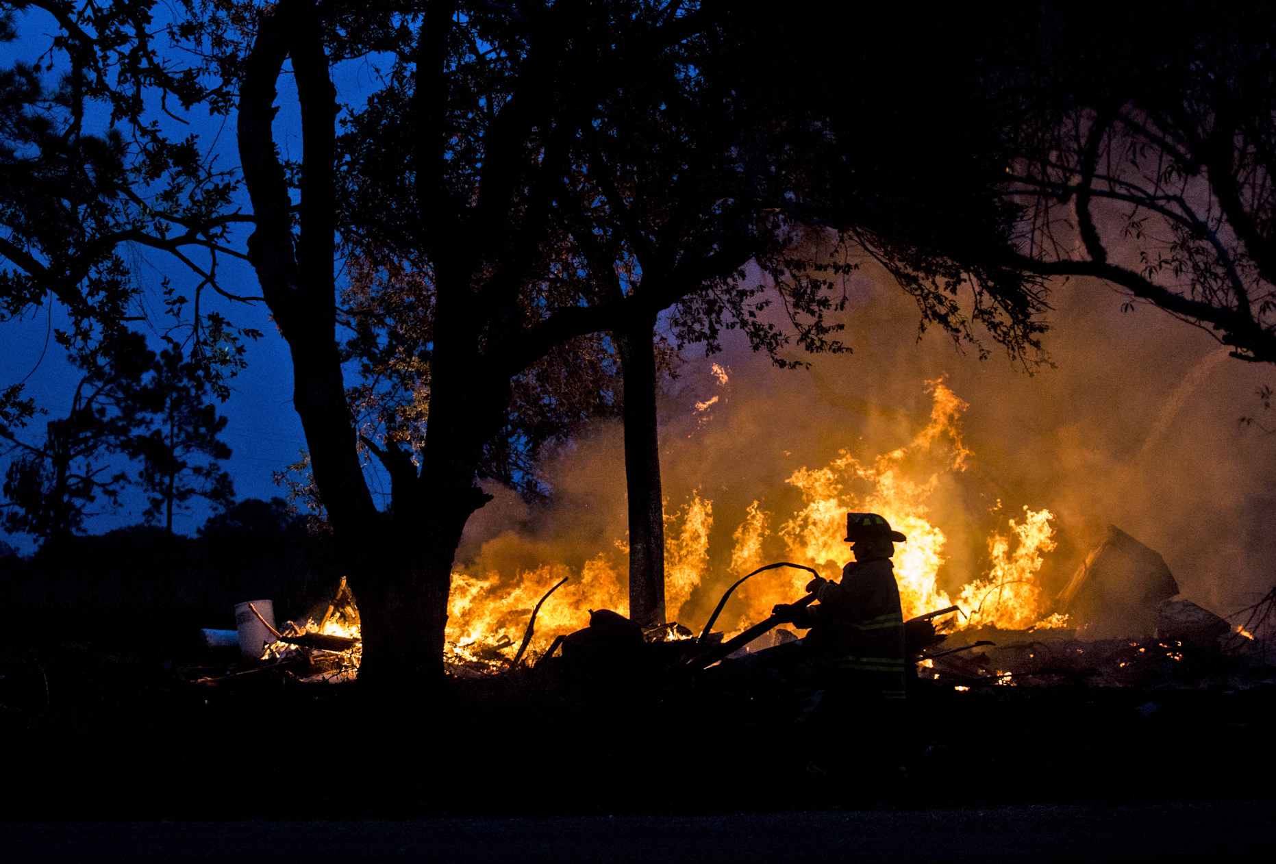  A firefighter drags a water hose closer to a house fire in the 300 block of U.S. Business 77 toward Refugio, Texas on Dec. 28, 2017. The abandoned home was set on fire by the property owner after he ran into complications with trying to have the hom