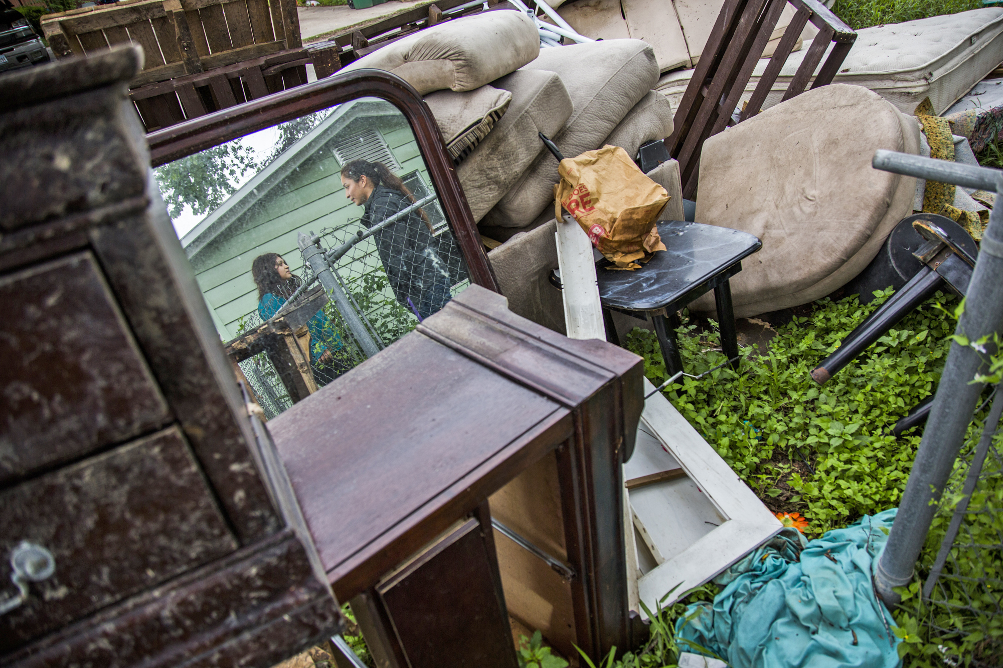 Samantha Torres, 23, left, and Jasmine Monroe, 24, right, stand outside of their home next to a pile of items they were forced to throw out after Hurricane Harvey caused widespread flooding, filling their home with water and damaging most of their belongings.