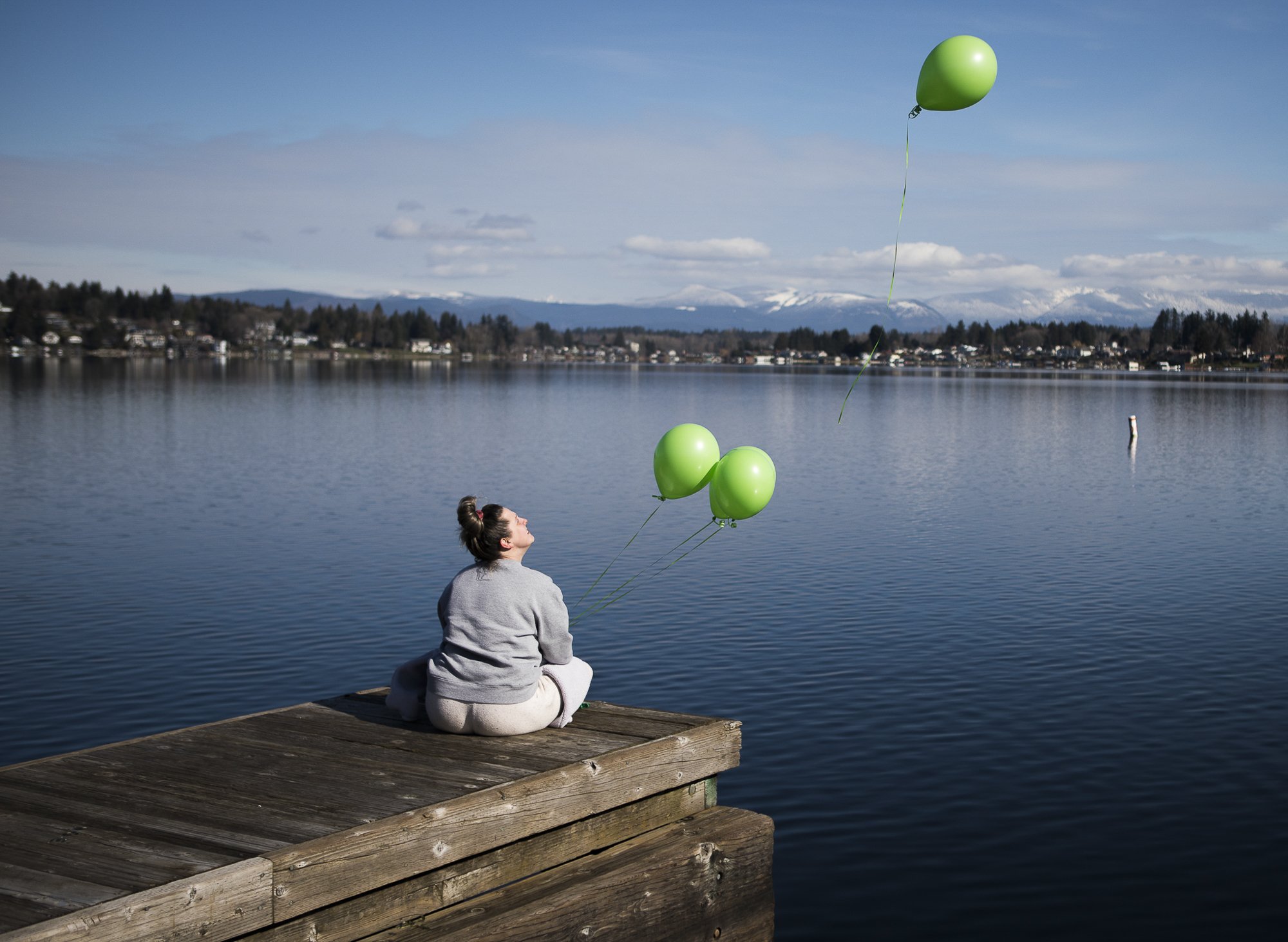  Ashley Olson releases green balloons from the dock at Davies Beach in memory of her brother, Joey Mell, who overdosed a year ago on Feb. 23, 2021 in Lake Stevens, Washington. Green was Mell’s favorite color and Olson describes her brother as “gorgeo