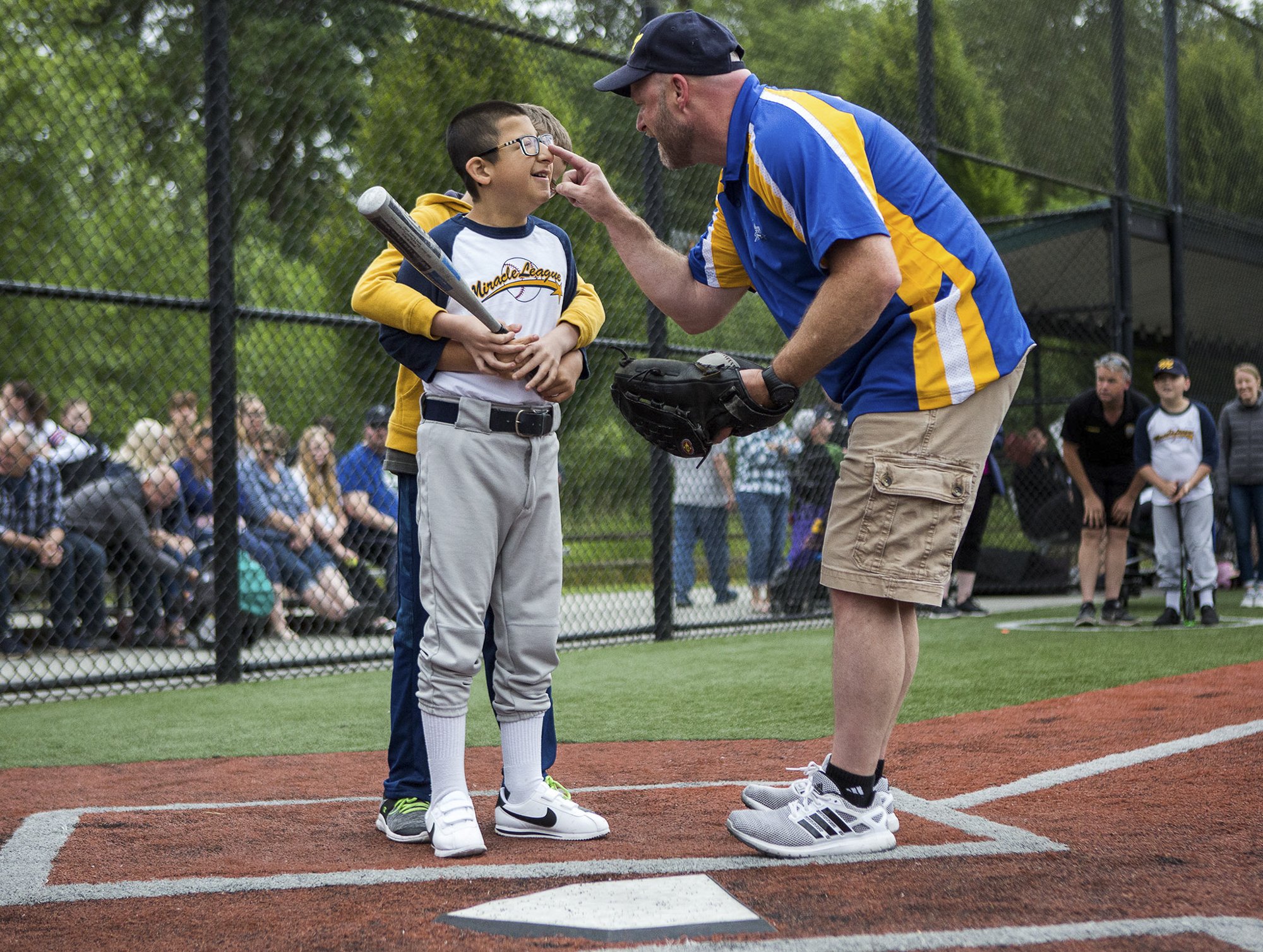  Angelo Chavez, 12, who has participated in Miracle League for 5 years, smiles as Coach Don Purvis taps his nose before his at bat during the final game of the season on June 15, 2018 in Monroe, Washington. 