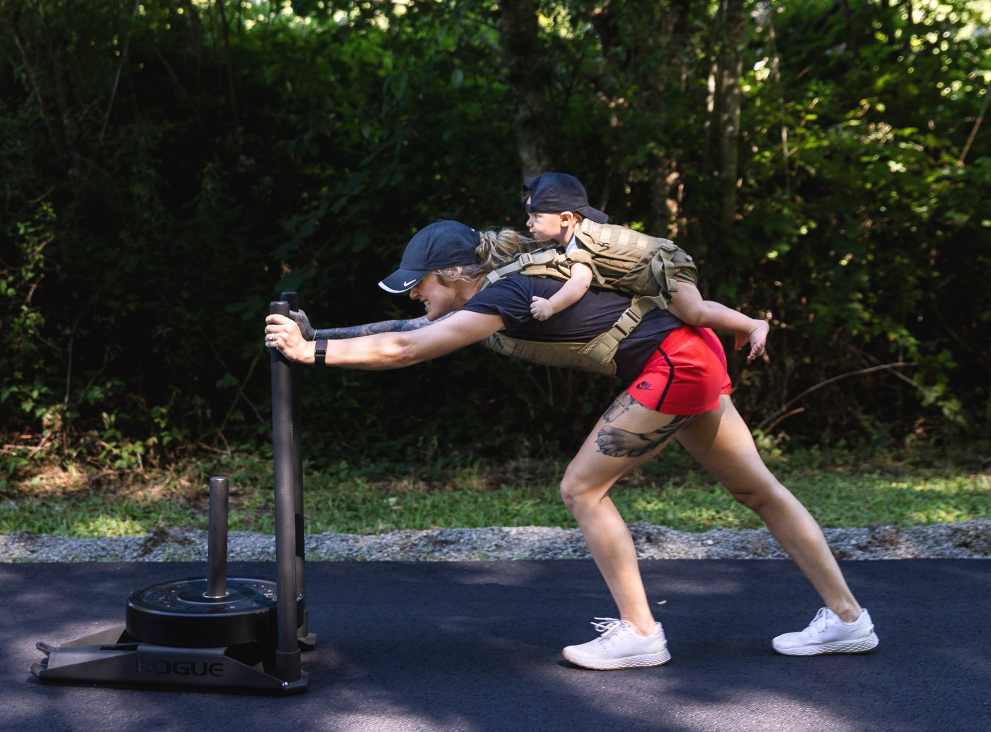  A few weeks before what could be her final professional UFC fight, Miranda Granger grimaces as she pushes a 45-pound plate up her driveway on Tuesday, July 12, 2022, in Lake Stevens, Washington. Her daughter Austin, age 11 months, is strapped to her