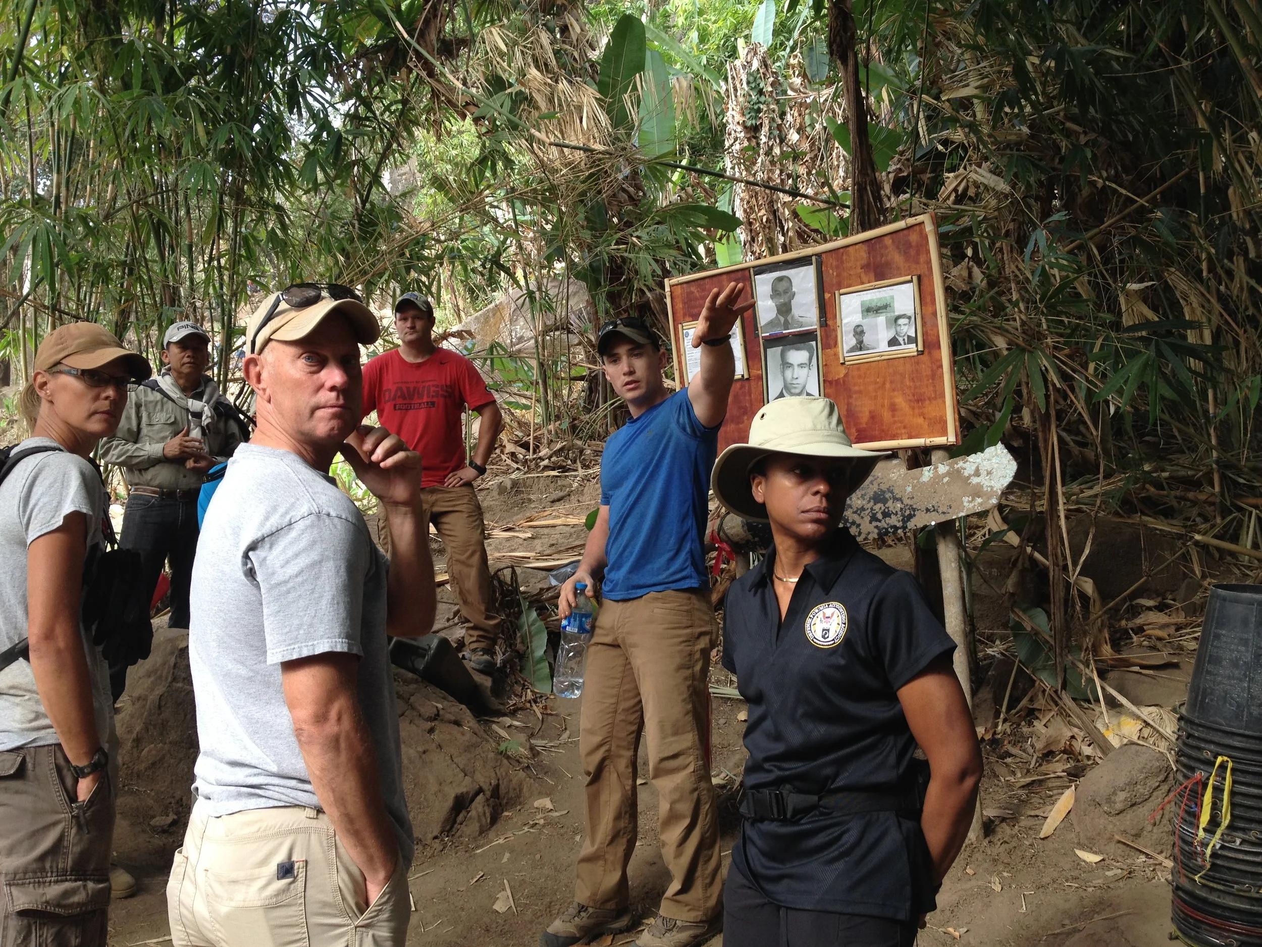 Fern Sumpter Winbush, right, looks toward a recovery site in Laos. Behind her is "the board," a standard practice at every recovery site that includes pictures of the missing and information about who was lost and the type of equipment they used. The crew working on a site assembles in front of the board every morning to remember why they are there. Photo courtesy DPAA.