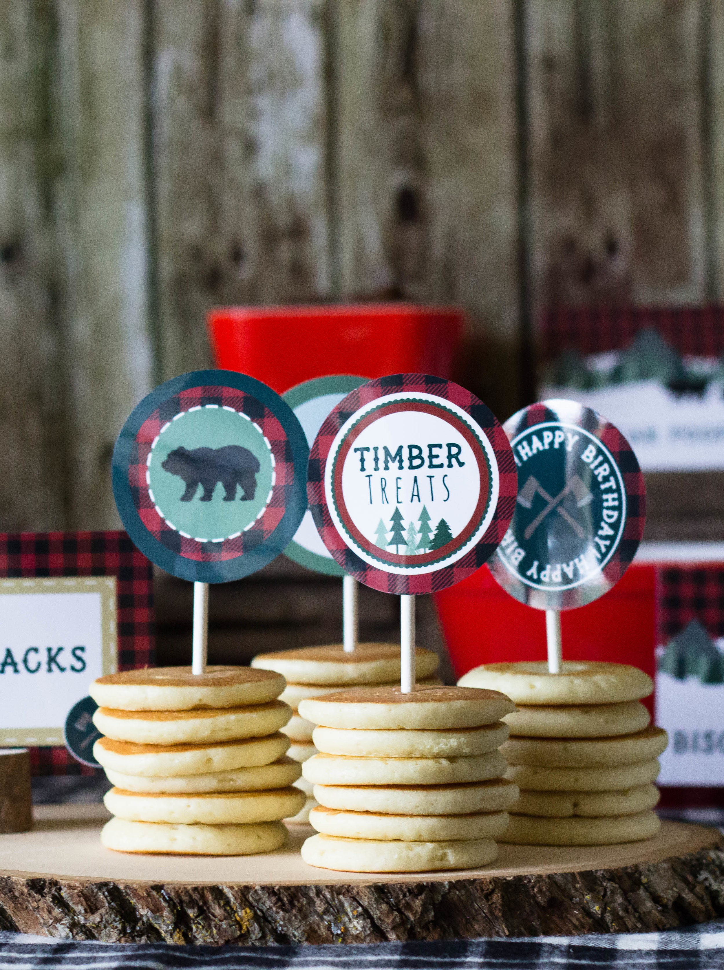 Lumberjack party decor at a rustic first birthday party. Use cupcake toppers on your pancakes to add a fun custom touch. // designs from shopmkkm.com
