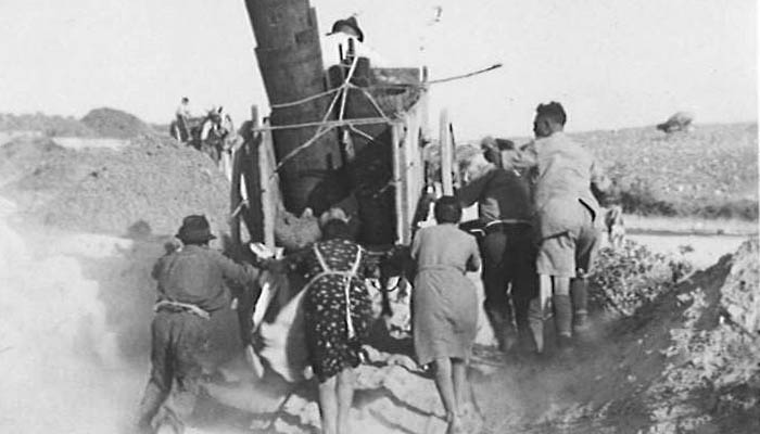  Seaforth soldiers assisting local Sicilian refugees with pushing their wagon full of household effects. 