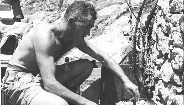 "Supper-time on the evening of the great assault on Agira by the Seaforth Highlanders of Canada finds Pte. R.M. Stinson of Vancouver, cooking a meal for himself his pals at Battalion HQ. The Seaforths made a nightlong attack on the outskirts of Agira and in the morning, men of the Edmonton Regt and PPCLI entered the city and captured it after a day of vicious street fighting. Date: 28 July 1943.