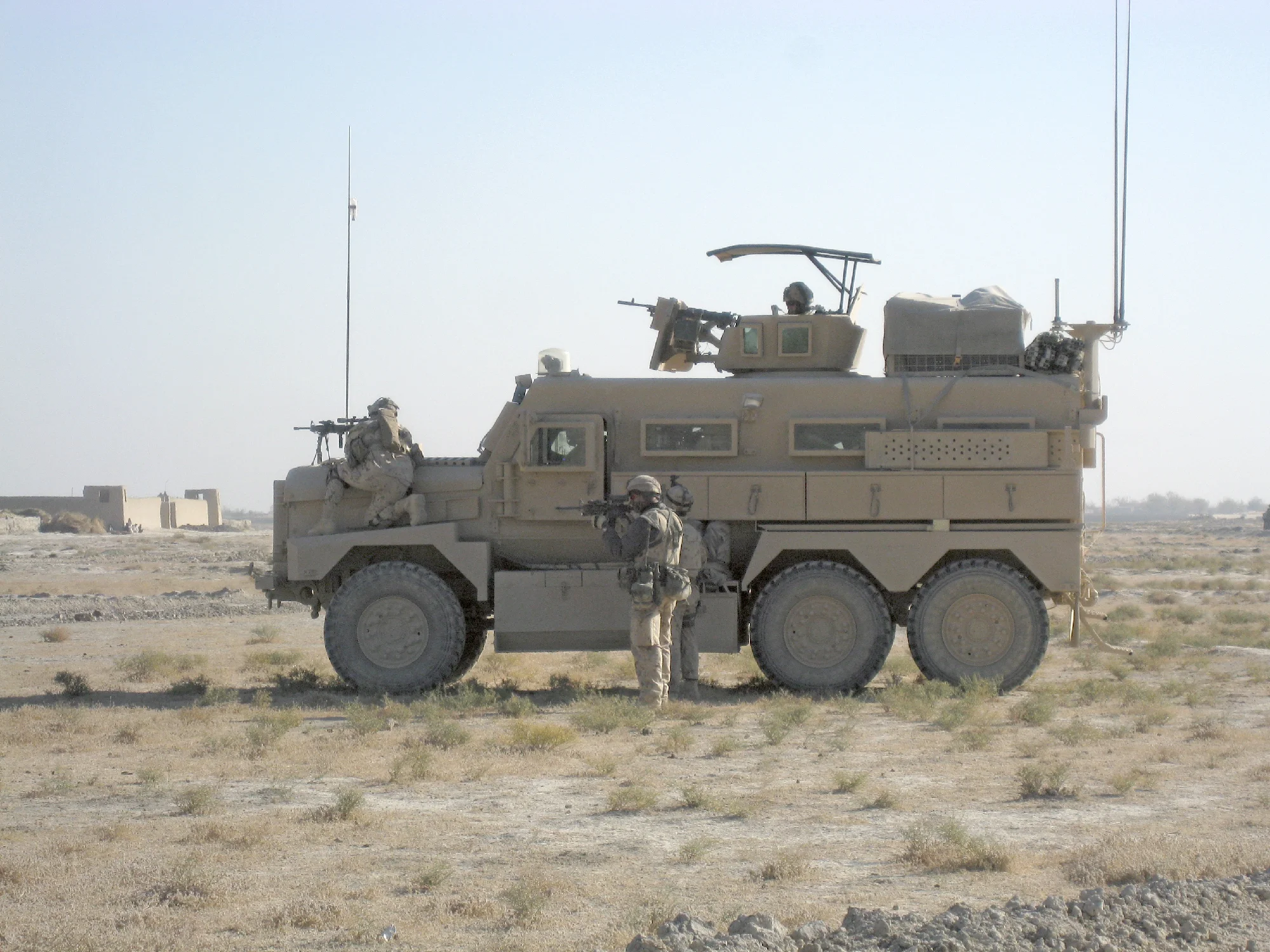 A Corporal of the Seaforth Highlanders has noticed suspect activity. He uses the fender of a Cougar to keep an eye on an individual who was paying unusual attention to the Canadian convoy outside the village of Nakhonay, Kandahar province, Nov. 2009. The vehicle was used by a Canadian Explosives Ordinance Disposal team.