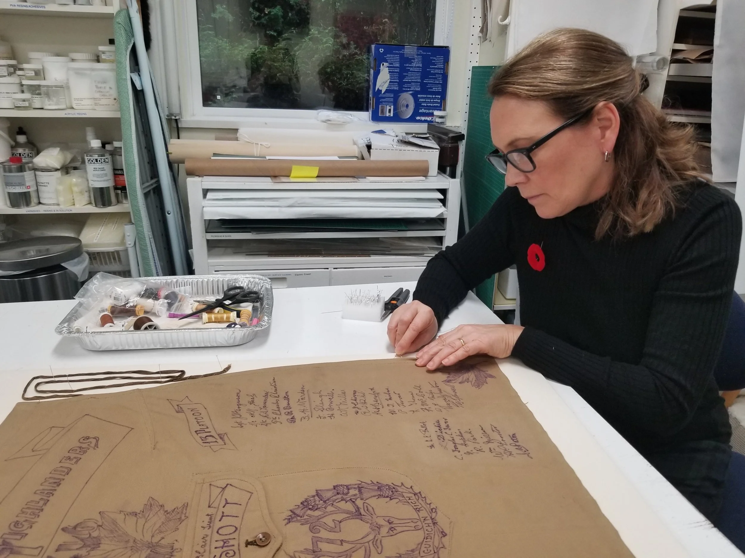 Conservator Sarah Spafford-Ricci sewing apron onto linen mount