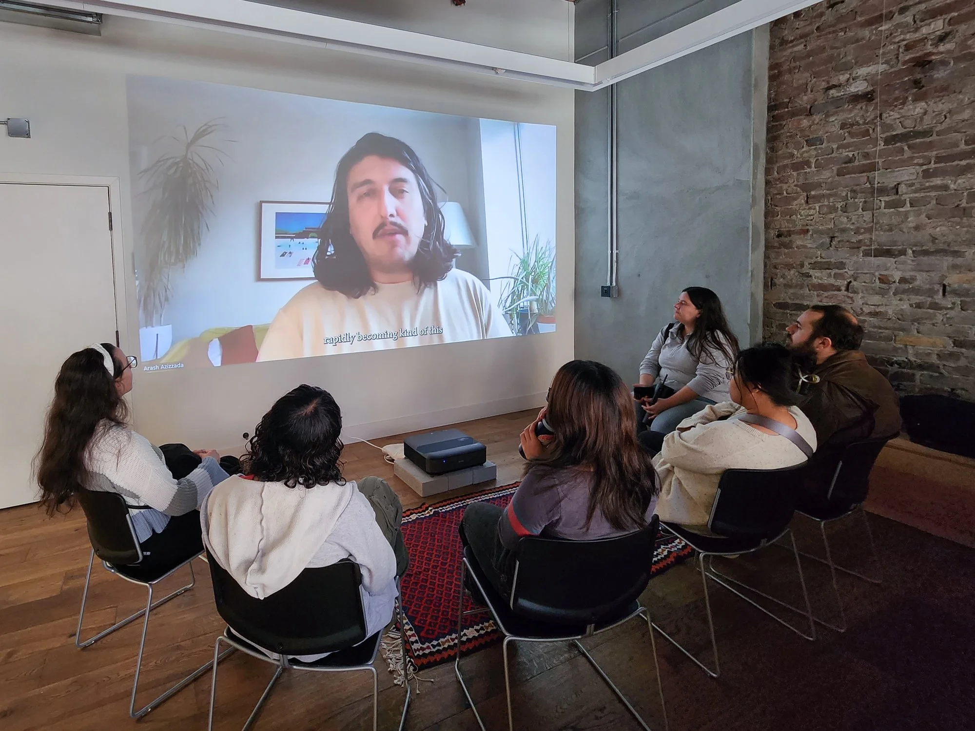  While waiting for the game to start, players watched interviews with advocates addressing Afghan refugees' challenges post-2021 US/NATO withdrawal. Pictured on screen: Arash Azizzada, co-founder of Afghans for a Better Tomorrow. 