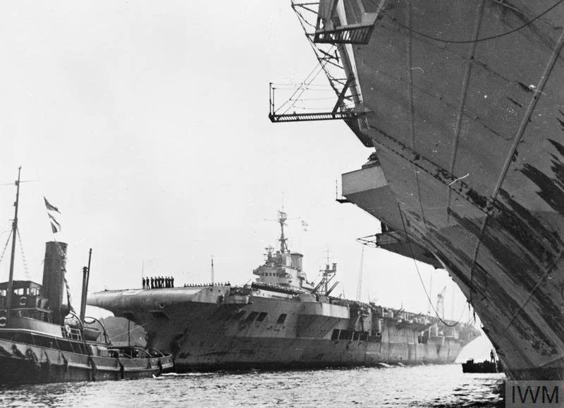 HMS Formidable is towed into her berth in Sydney on 24 August 1945, returning with units of the British Pacific Fleet after Japan’s defeat, seen alongside a sister carrier. Source: Imperial War Museums (IWM A 30364).