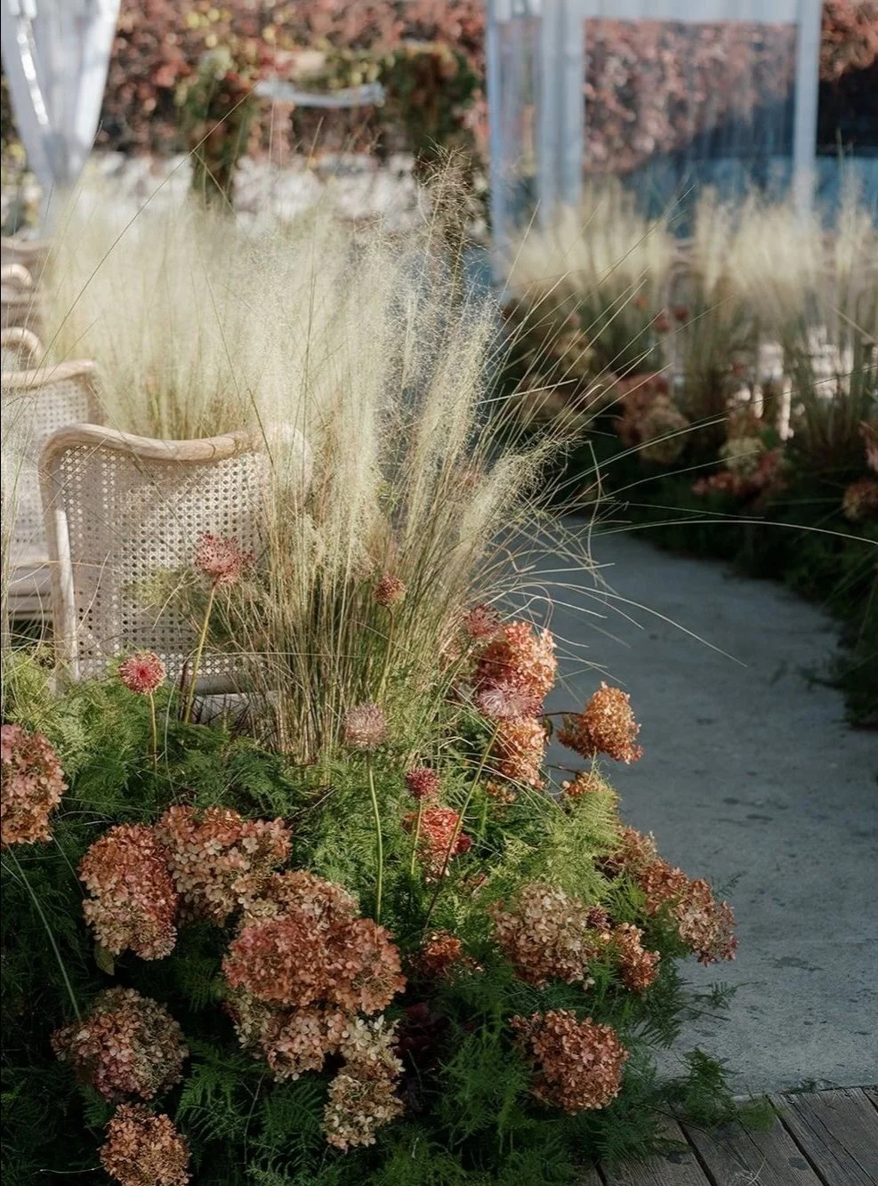 Dusty red hydrangeas detailed with tall grasses line the aisle on this wedding day. 
Designed by Blxxm Flori.

#floraldesign #weddingflorals #flowertrends #weddingdecor #wedddinginspo #milkbooks #rachelbeharevents #nylbfw