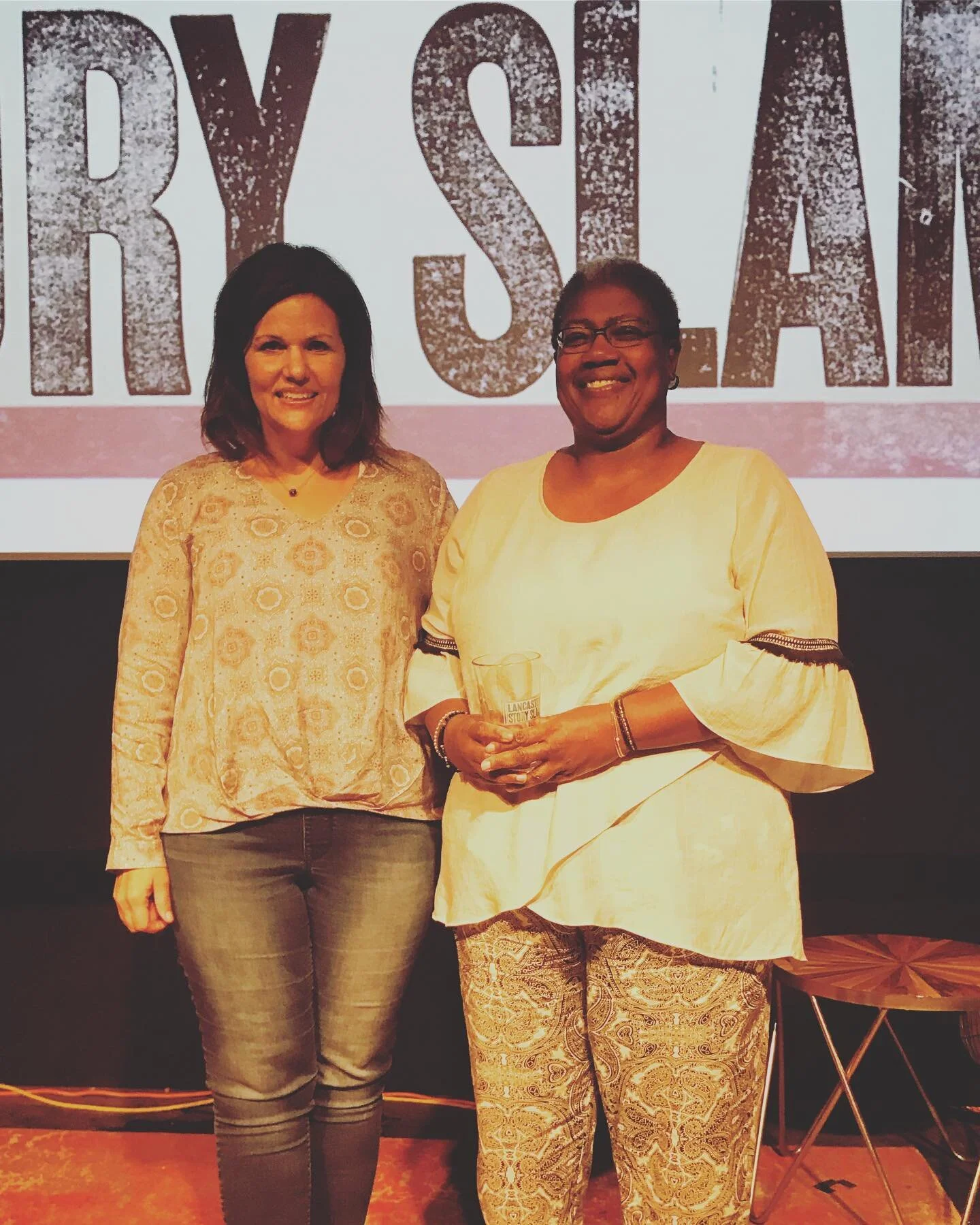 Emcee Luanne Sims congratulates Rita Clarke for winning the prized pint glass for her ‘Teach Your Children’ story!