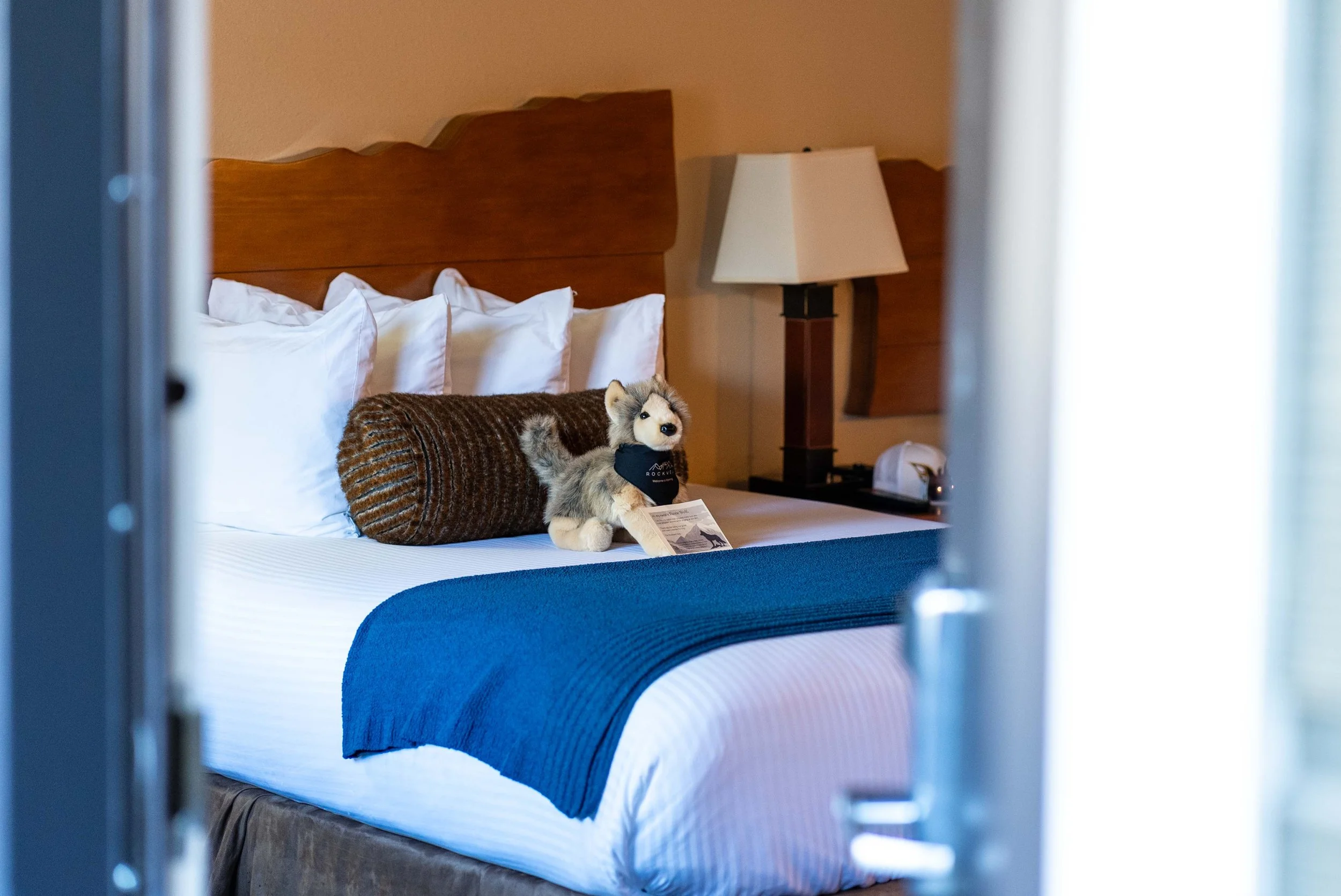 Hotel room door open to see bed and stuffed animal
