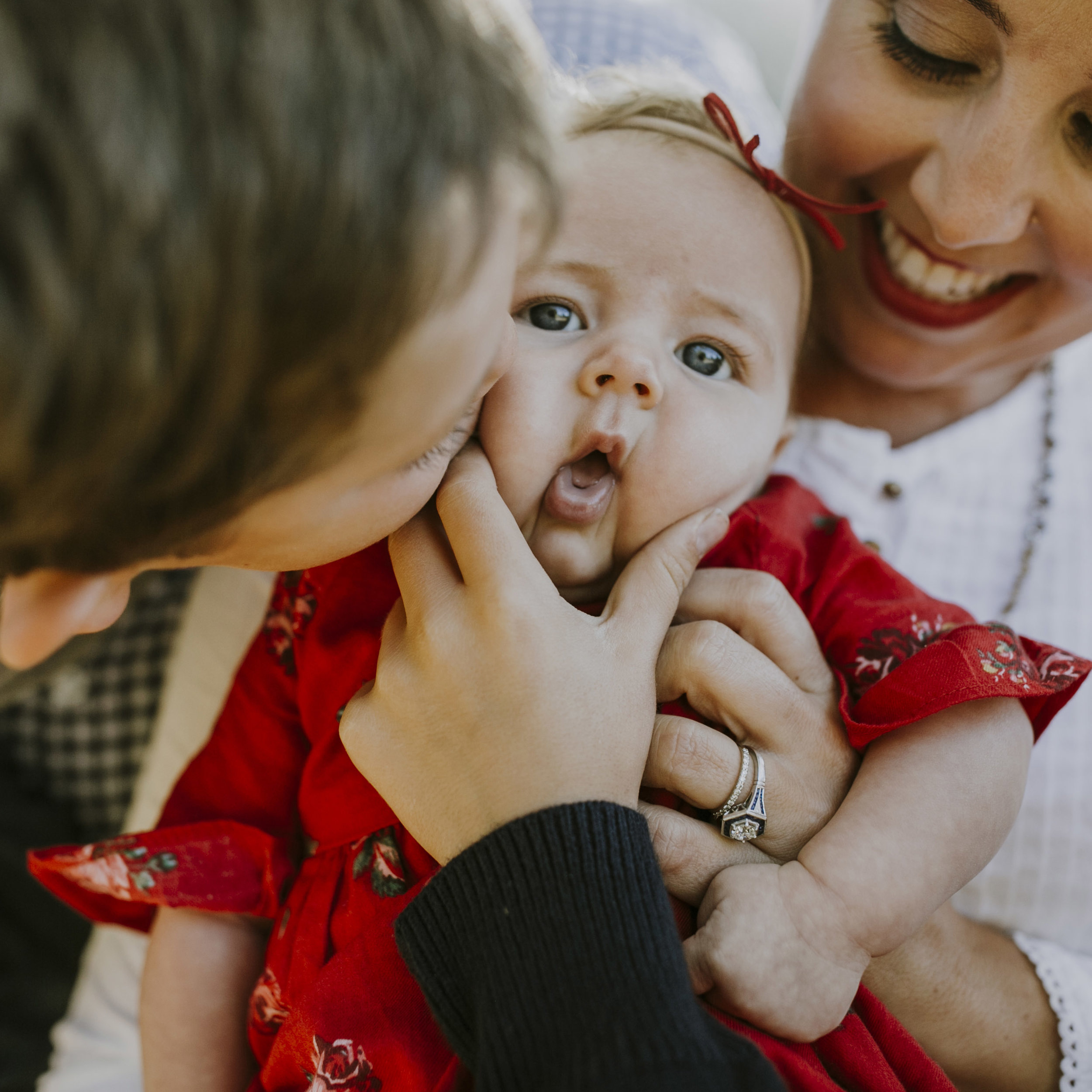 baby girl being held by mom and squished kissed by big brother funny family photo.jpg