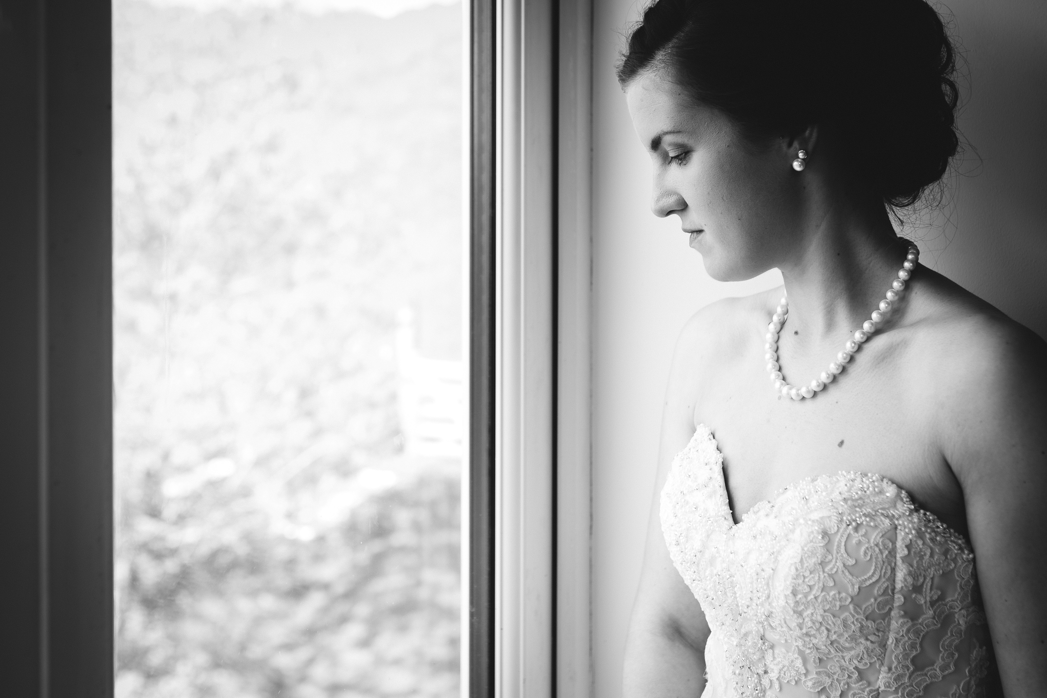 Bride in wedding dress looking out of window - Wedding Photography