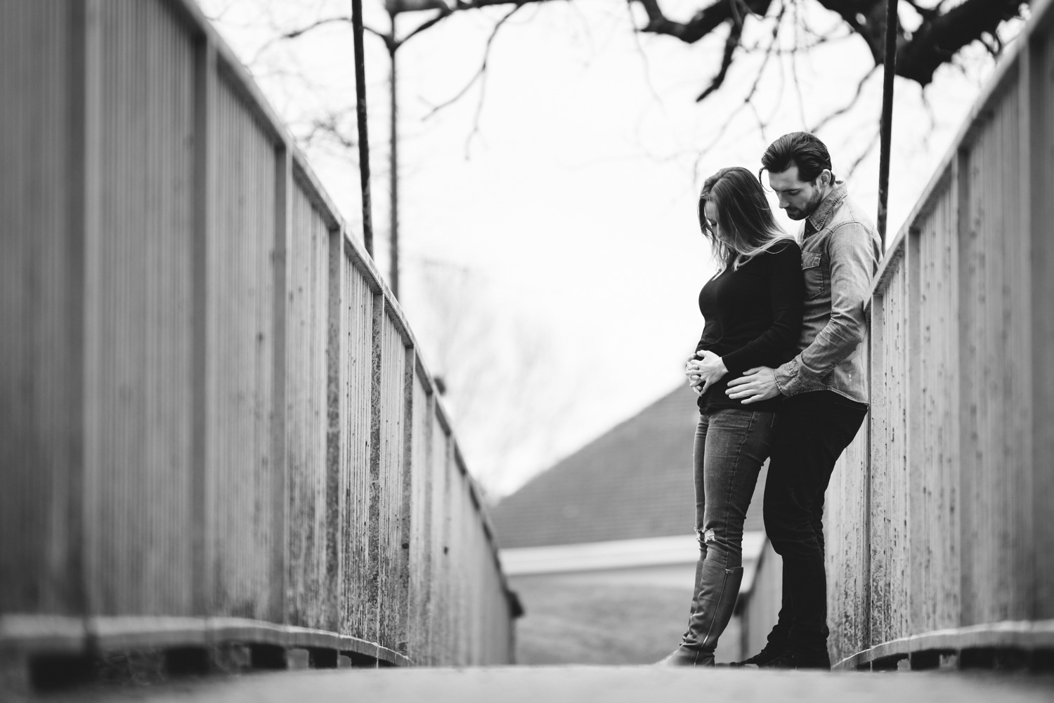 Couple stood on bridge holding baby bump