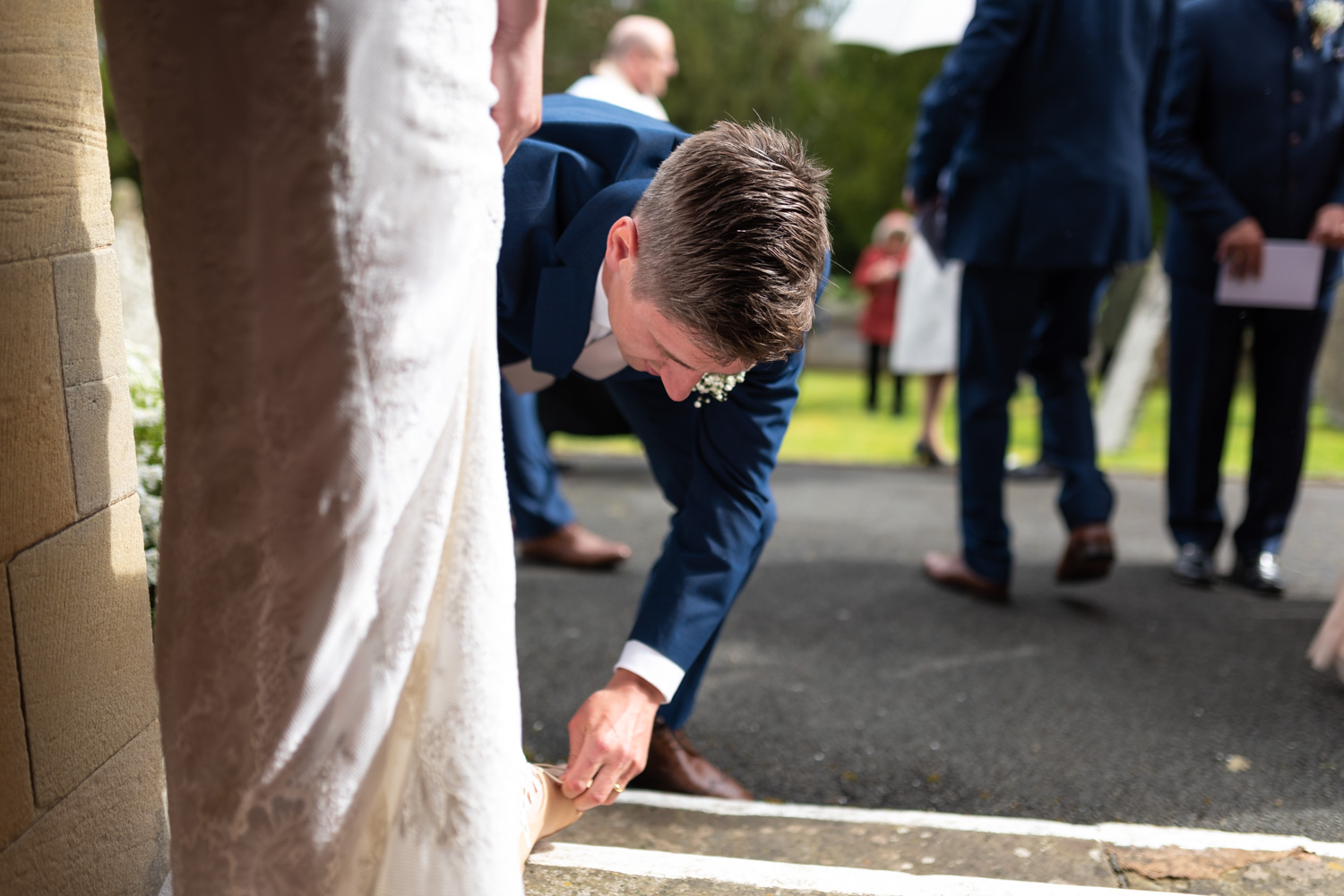 Groom tying brides shoes up