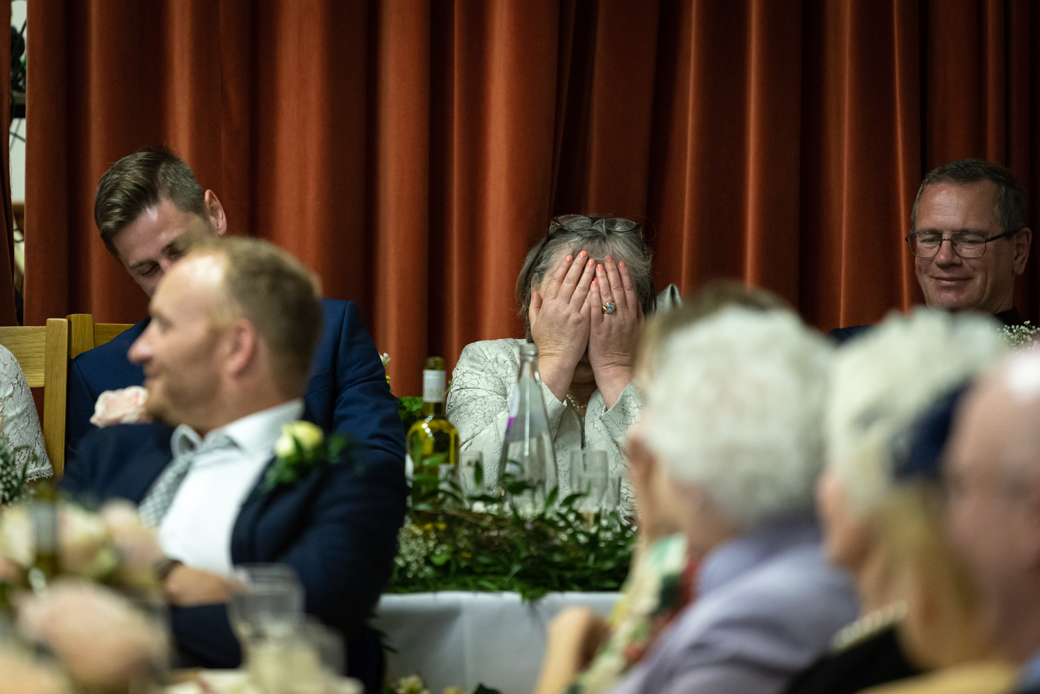 Mother of the bride with head in hands during speeches 