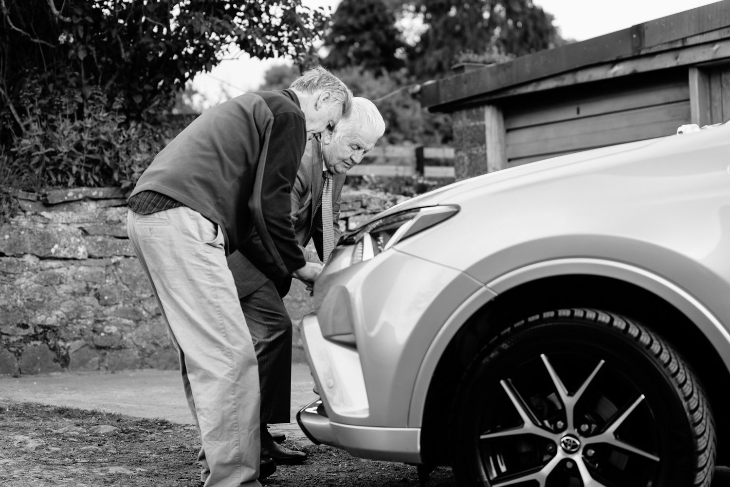 Two old men tying ribbon to car