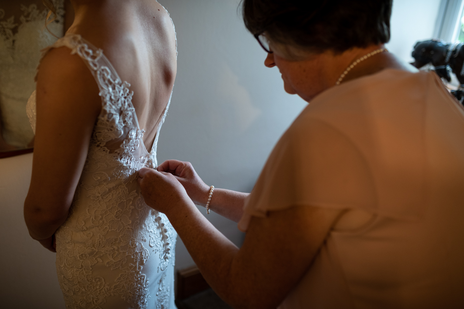 Mother doing back of brides dress up