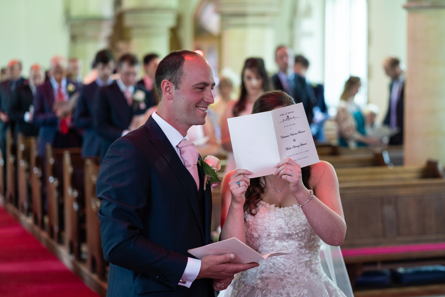 Bride hiding behind order of service