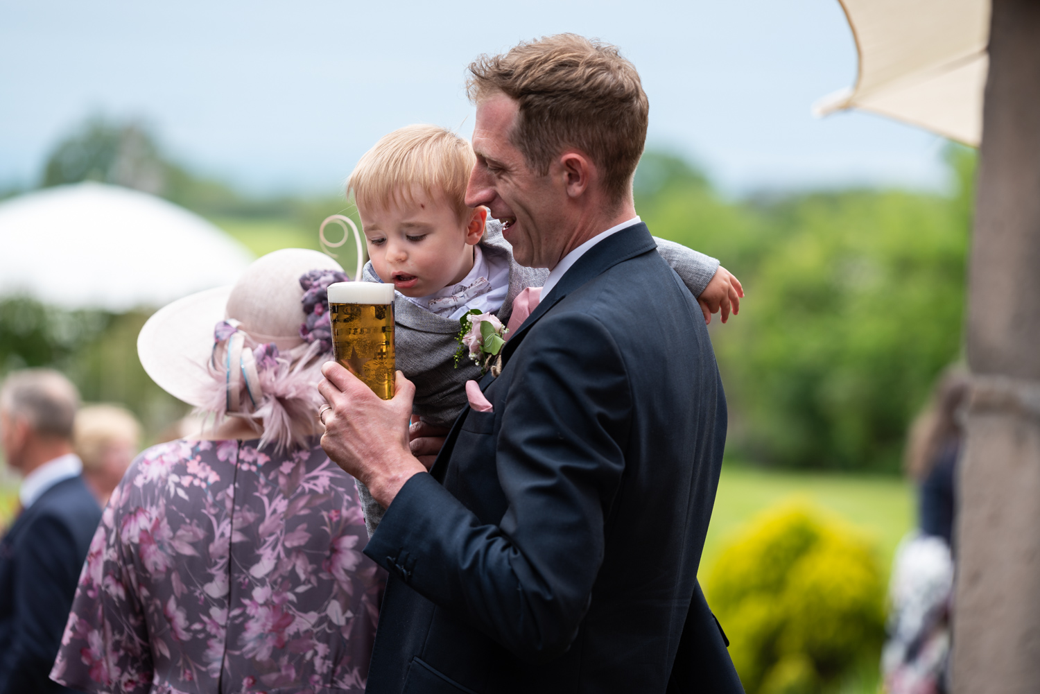 Baby trying to drink beer at wedding