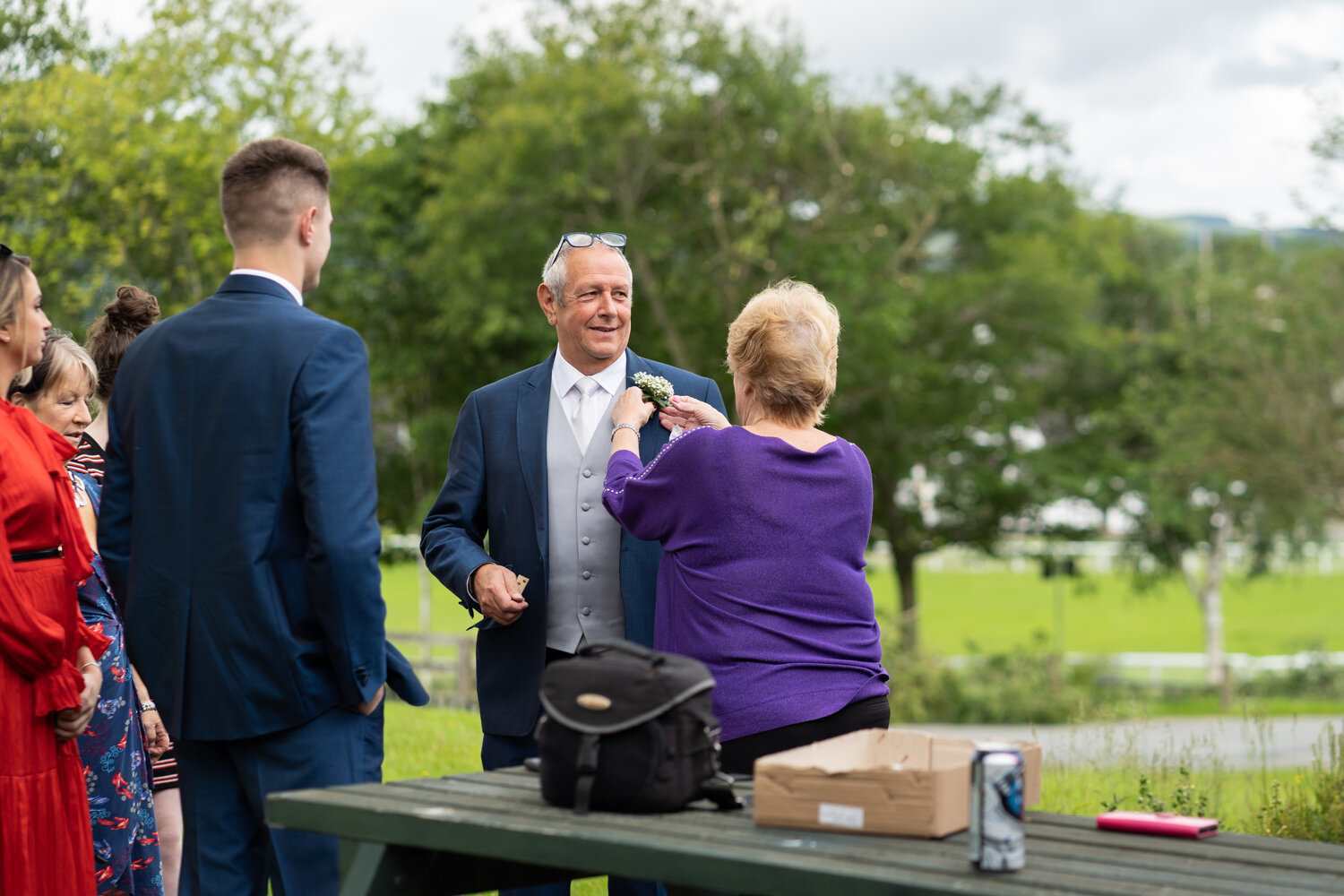 Father of bride having flower put on jacket